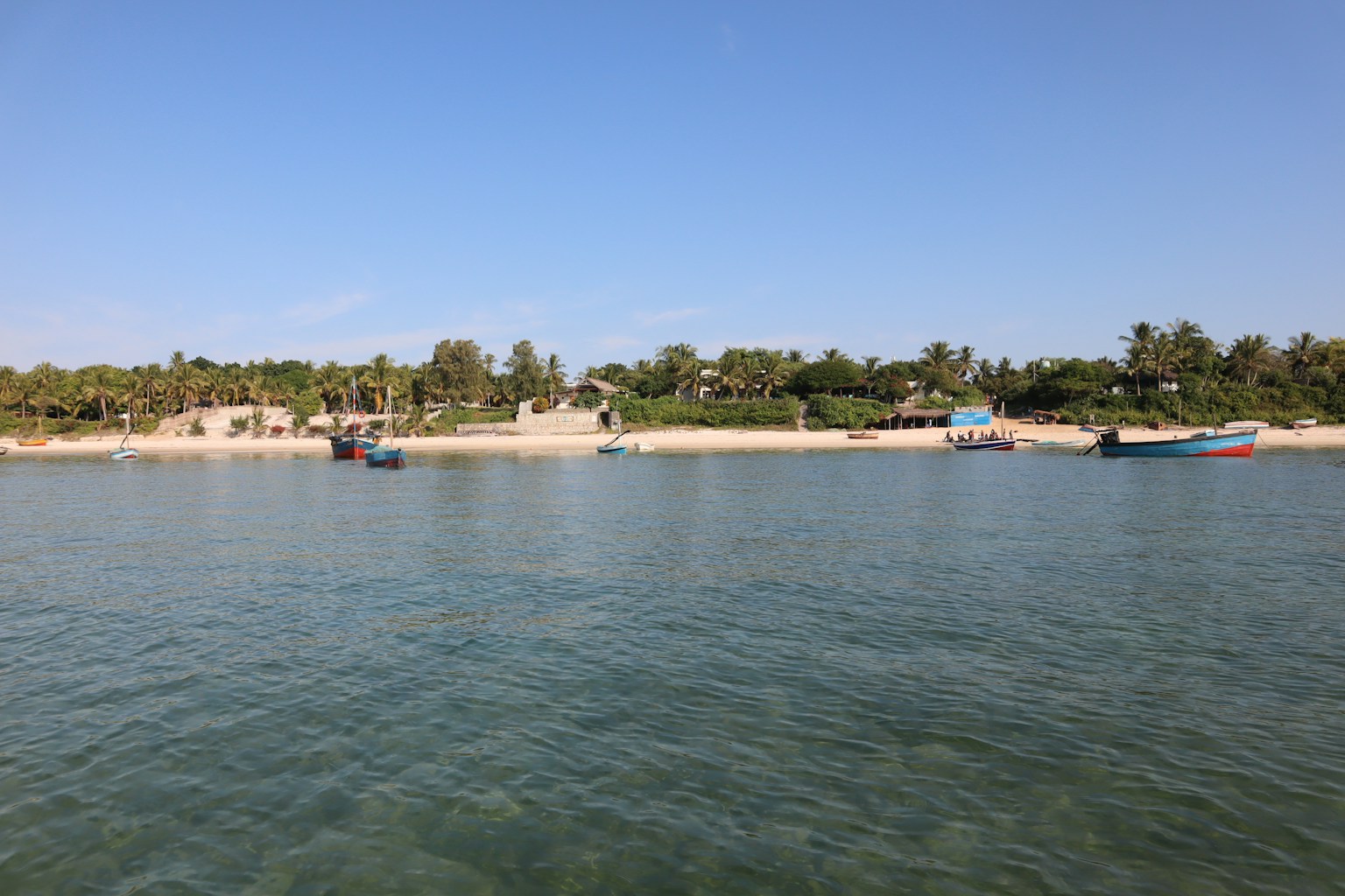 ทิวทัศน์ชายหาดที่งดงามพร้อมน้ำสีฟ้าและทรายขาว เรือที่จอดอยู่
