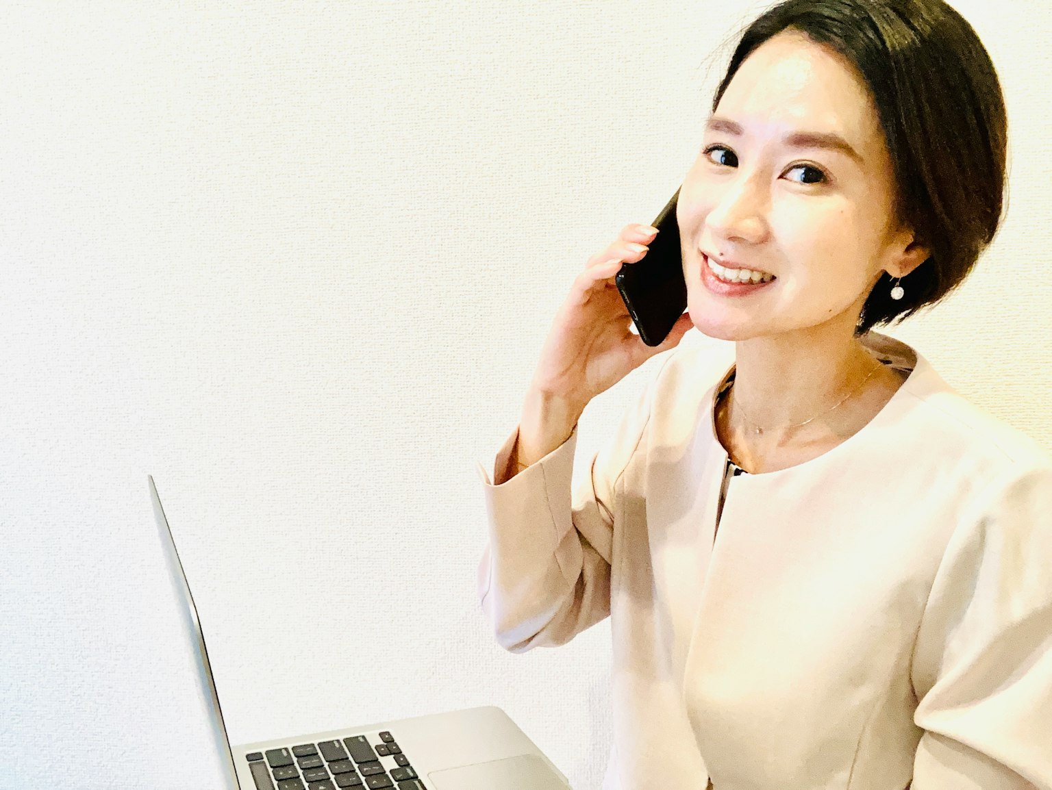 Seorang wanita berbicara di telepon sambil duduk di depan laptop