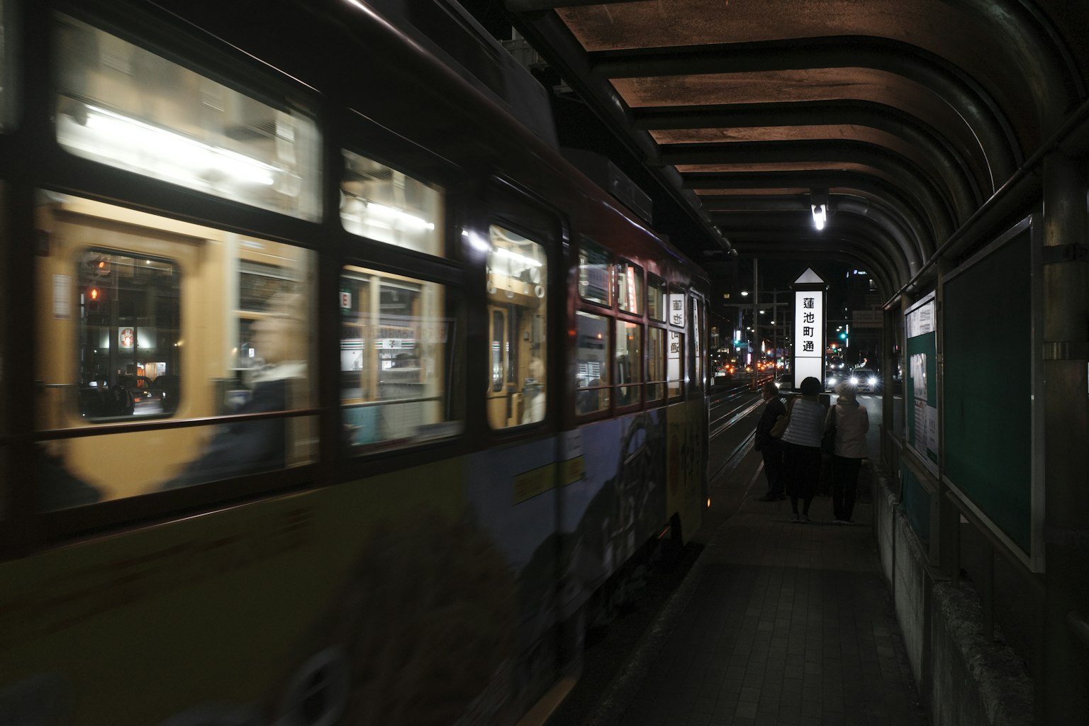 Tren ligero moviéndose a través de un túnel oscuro con personas cercanas