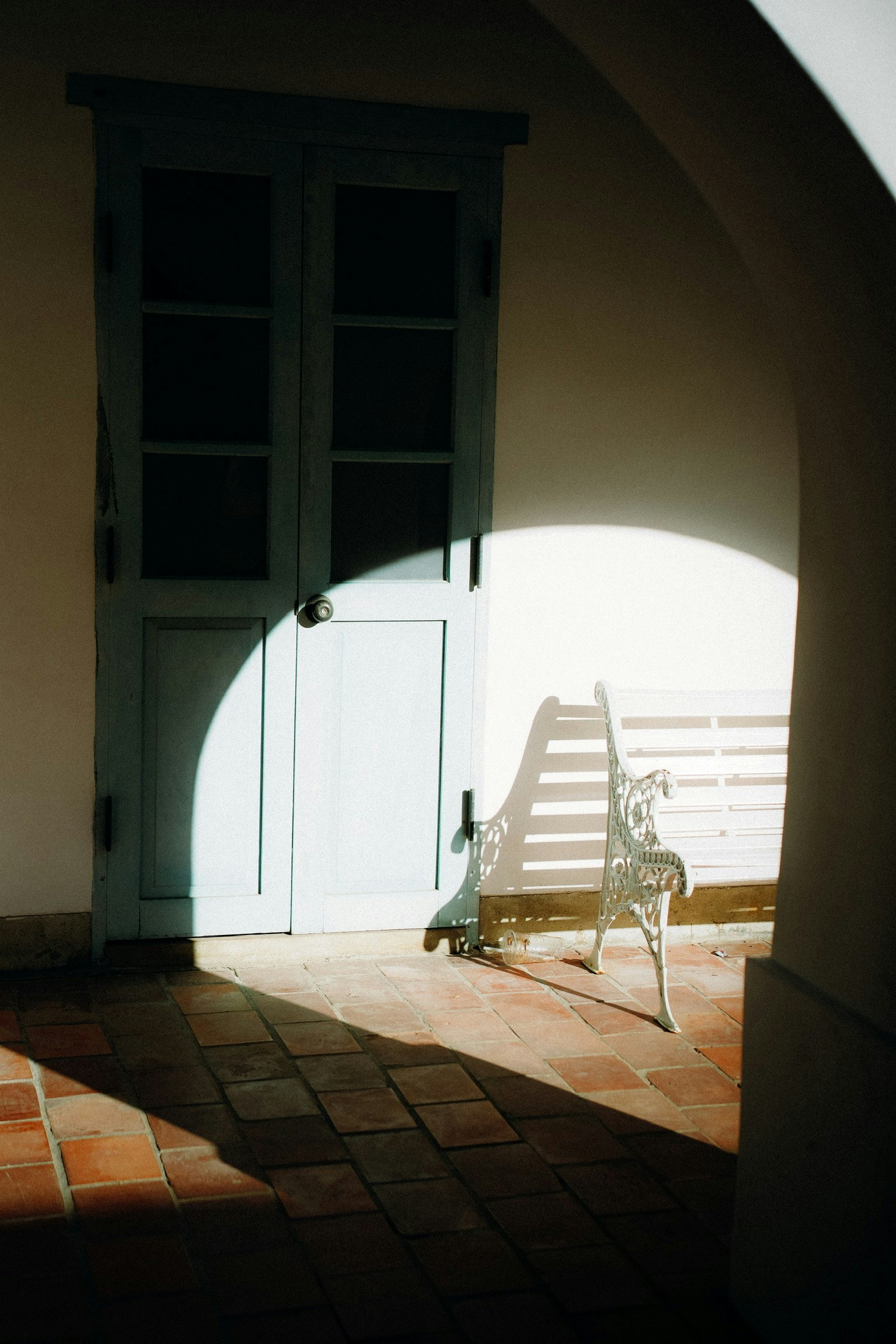 Escena interior con una puerta azul y una silla blanca proyectando sombras