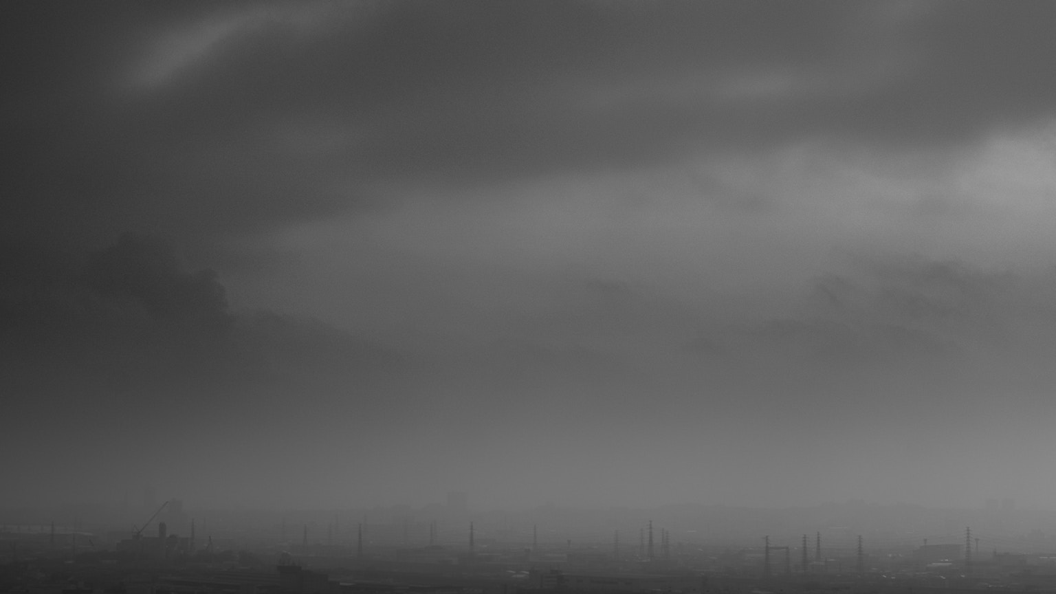 Black and white landscape with clouds and distant silhouettes