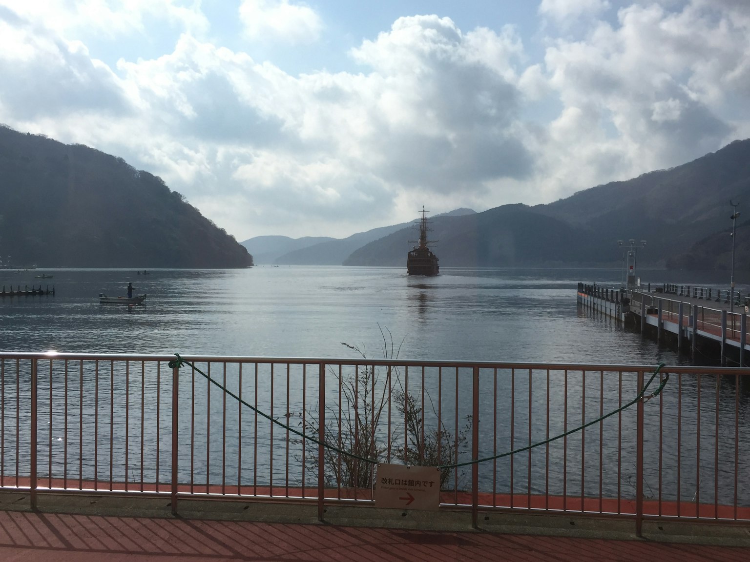 宁静的湖泊景观，四周环绕着山脉，远处有一艘船