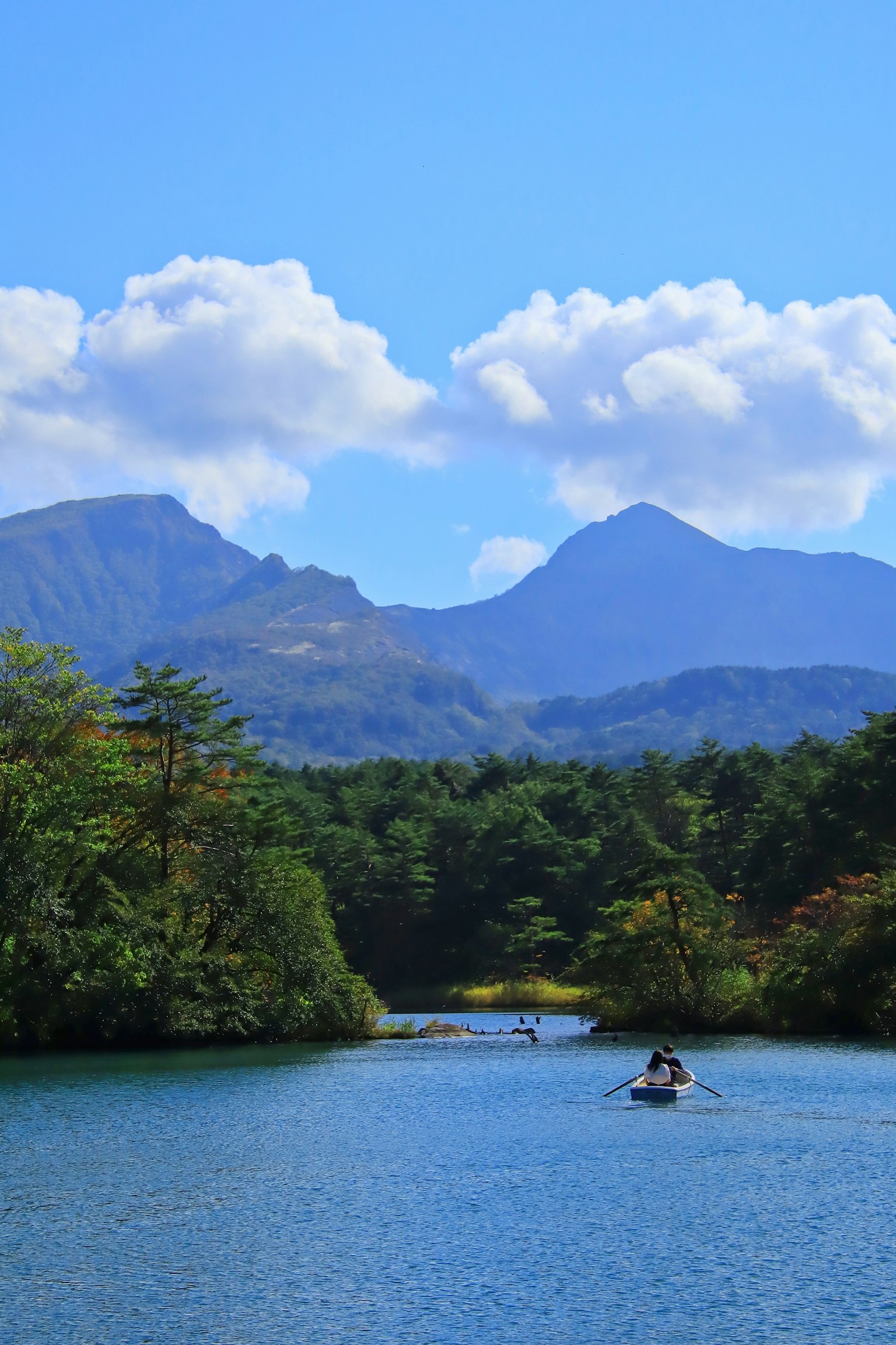 Vue pittoresque de montagnes et d'une rivière tranquille avec un bateau sous un ciel bleu