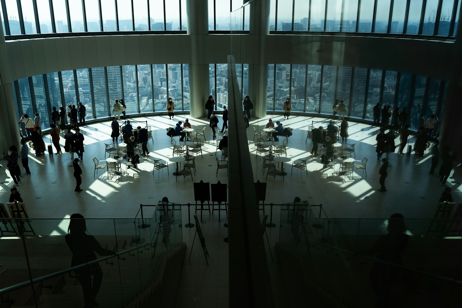 Crowd of people at a high-rise observation deck Bright light illuminates the interior from large windows