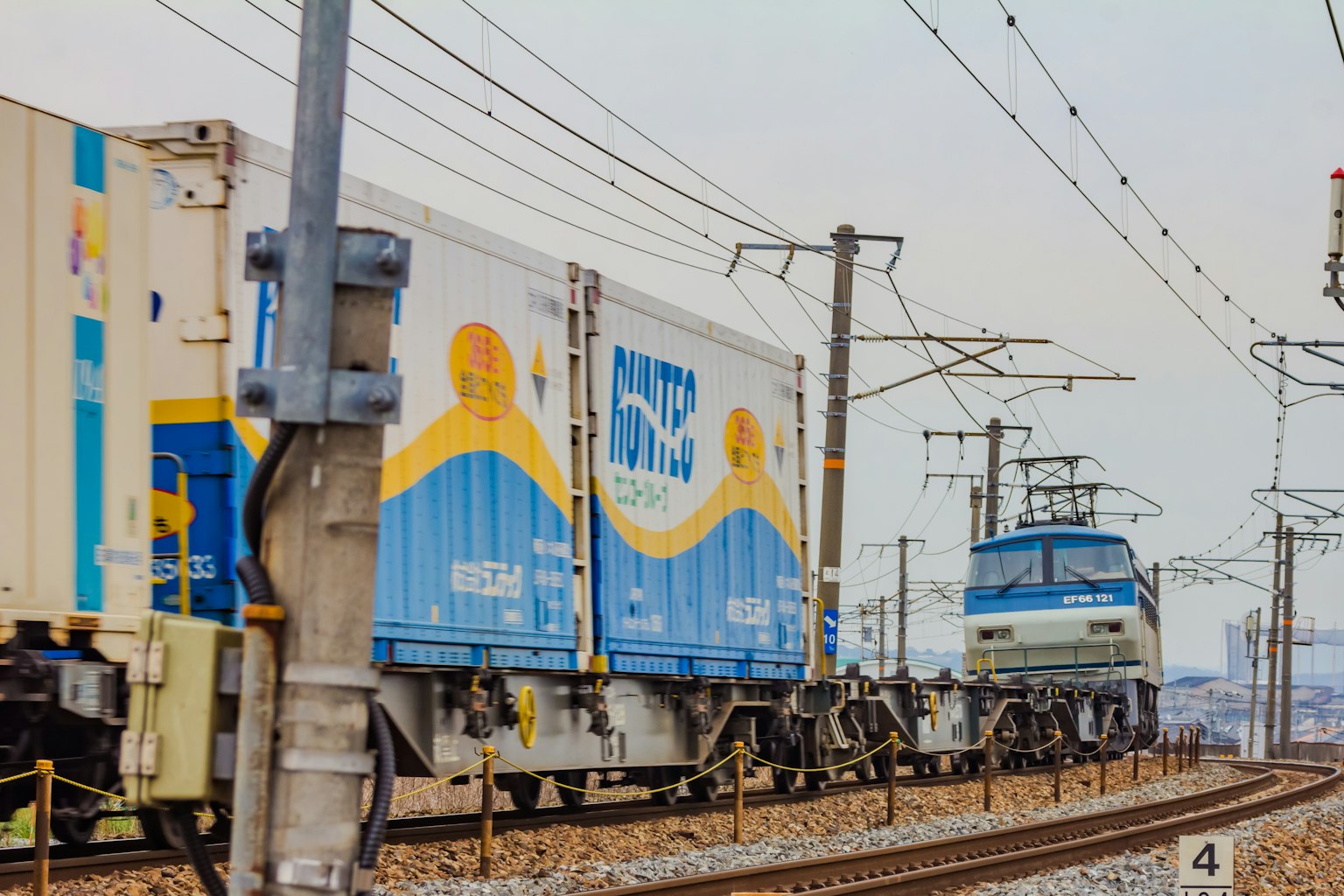Un tren azul tirando contenedores de carga a lo largo de las vías