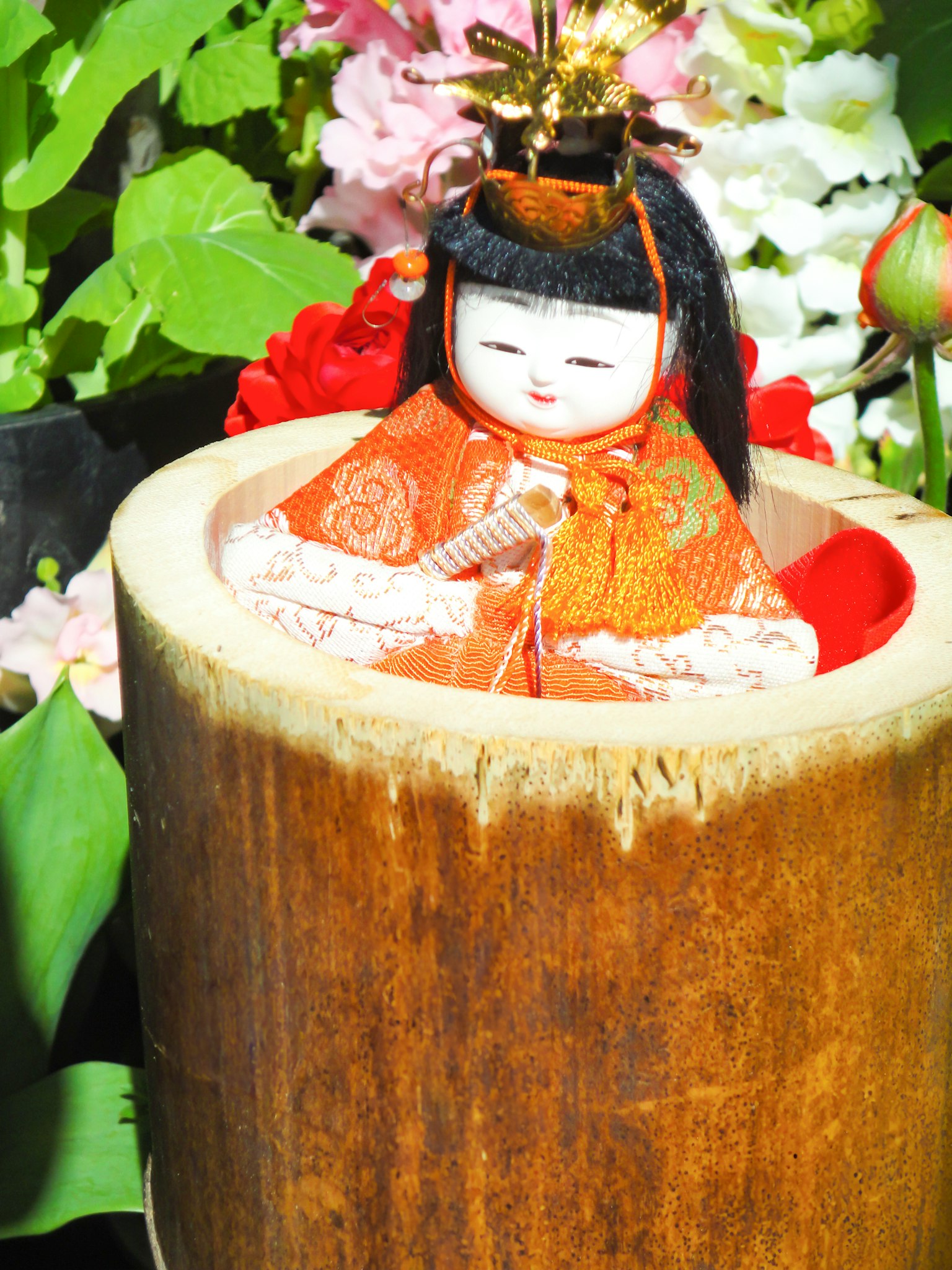 坐在竹子里的日本娃娃，周围是五彩缤纷的花朵