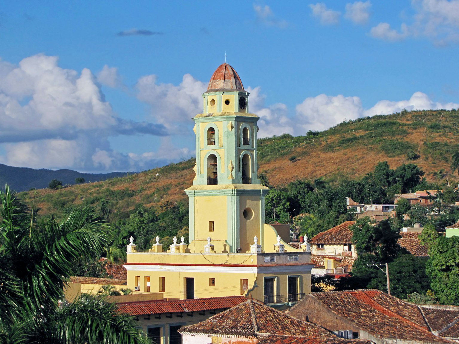Menara gereja berwarna di Trinidad dengan bukit di sekitarnya