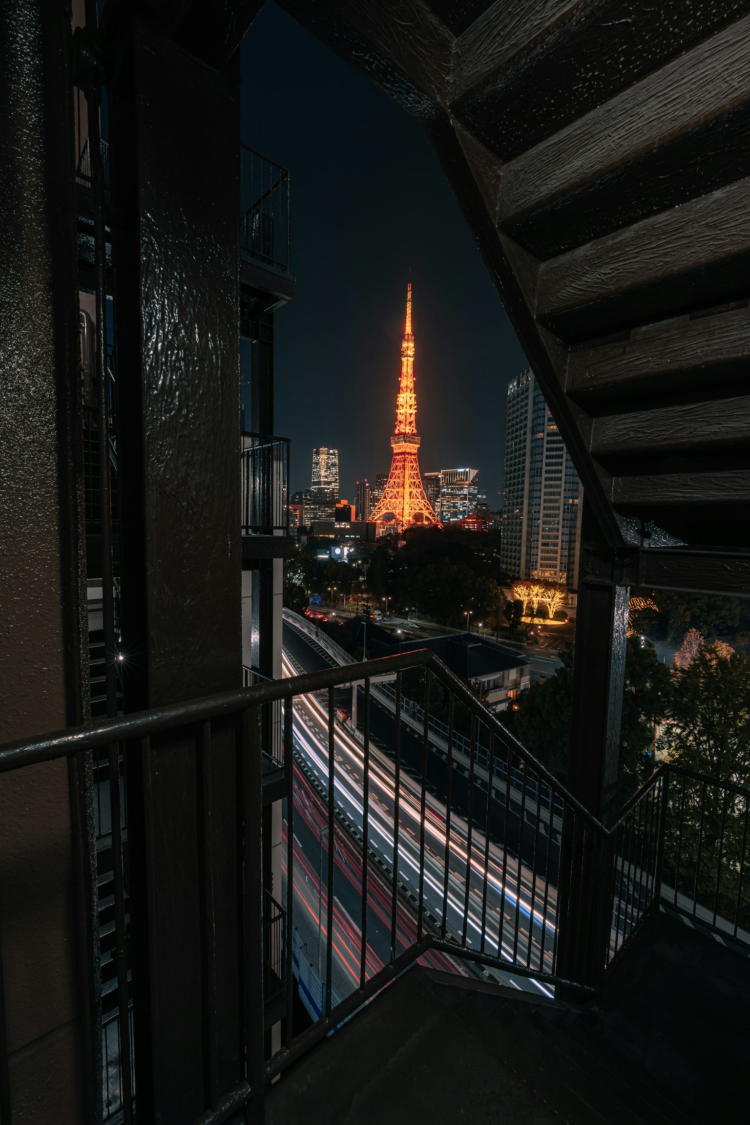 Vue de la Tour de Tokyo illuminée la nuit depuis un escalier en métal