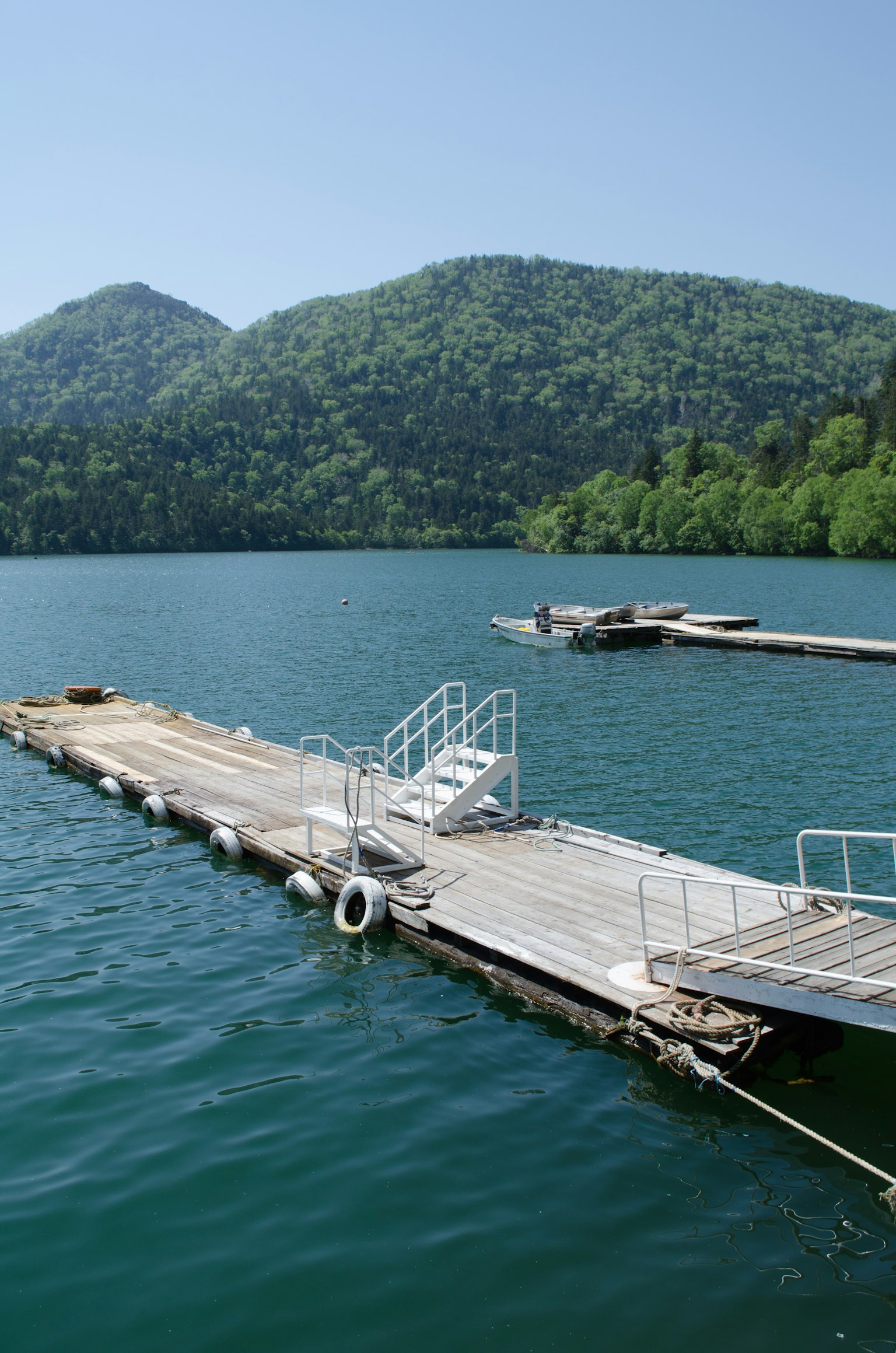 Dock on blue water with lush green mountains in the background