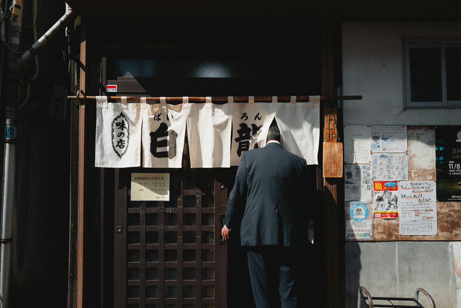 和風のレストランの入り口に立つ男性の背中と暖簾