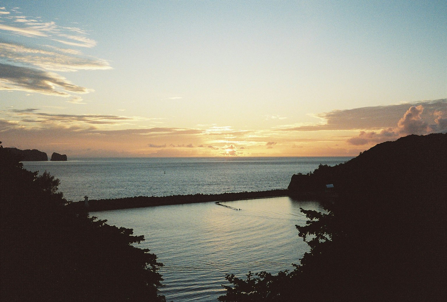 Scenic view of a sunset over the ocean with lush greenery and calm waters