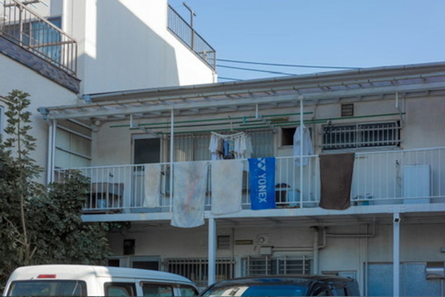 Balcone di un appartamento bianco con biancheria stesa e un'insegna blu