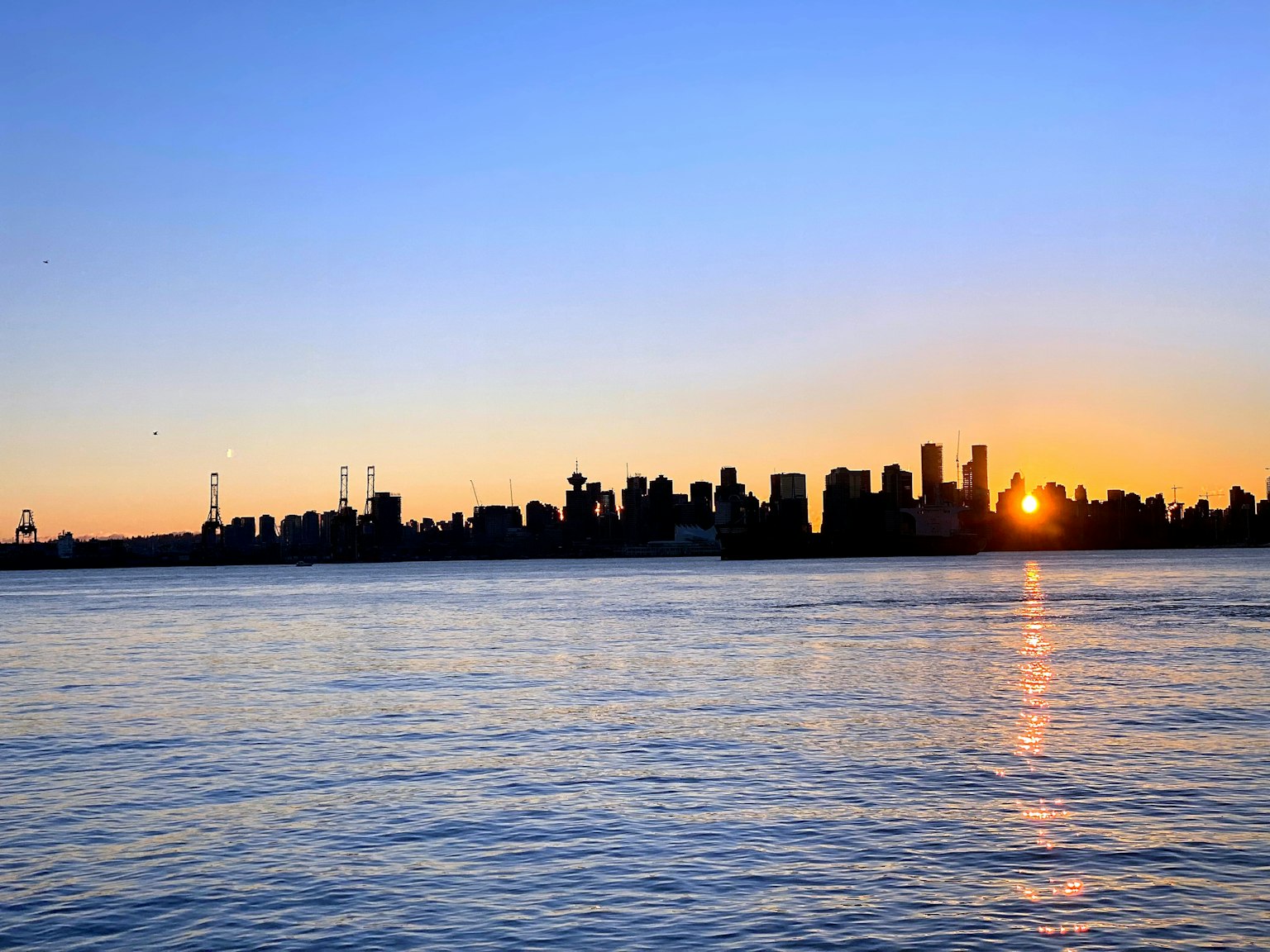 Città skyline al tramonto con acqua calma che riflette i colori