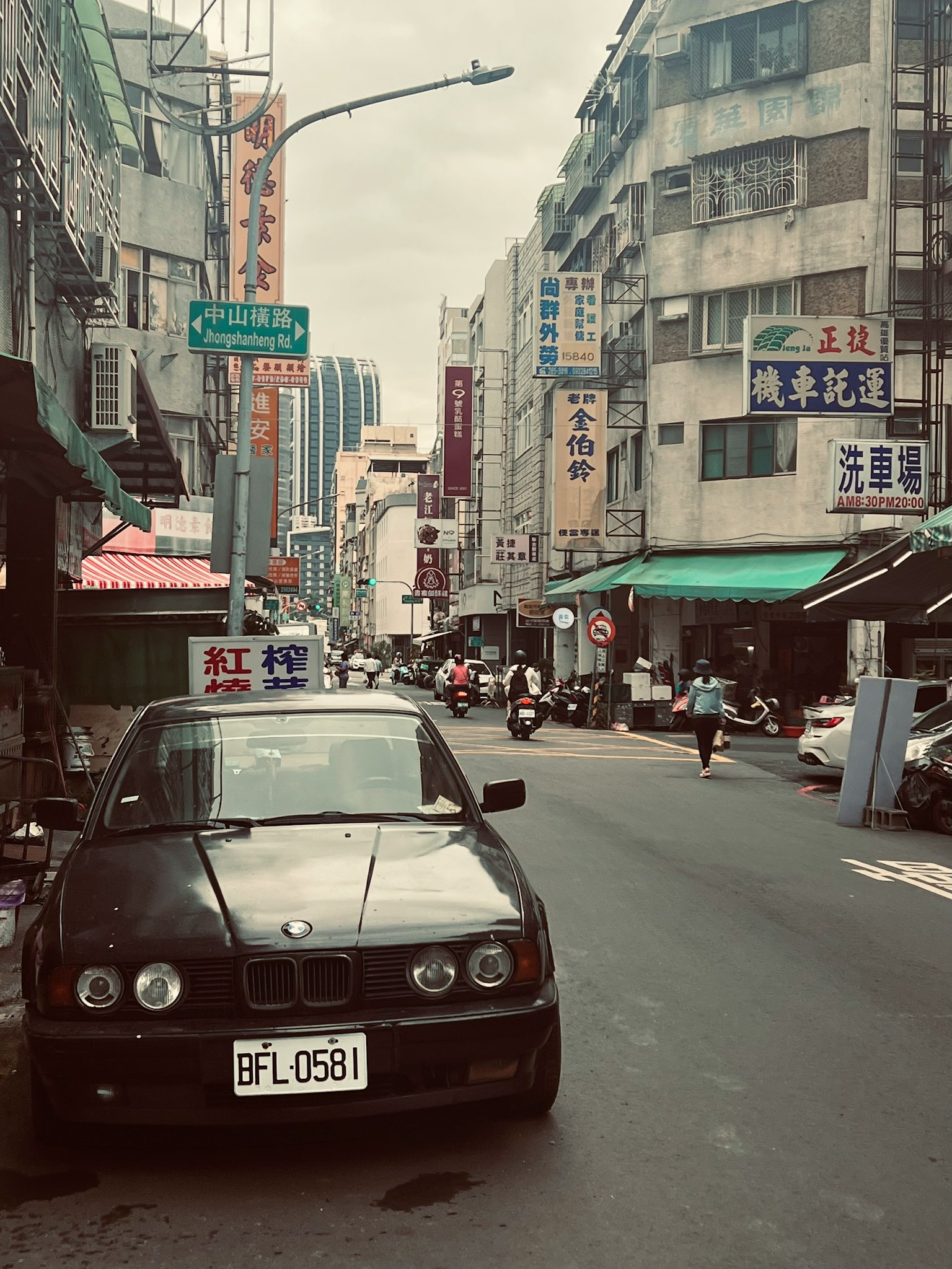 Black car parked on a street with surrounding buildings