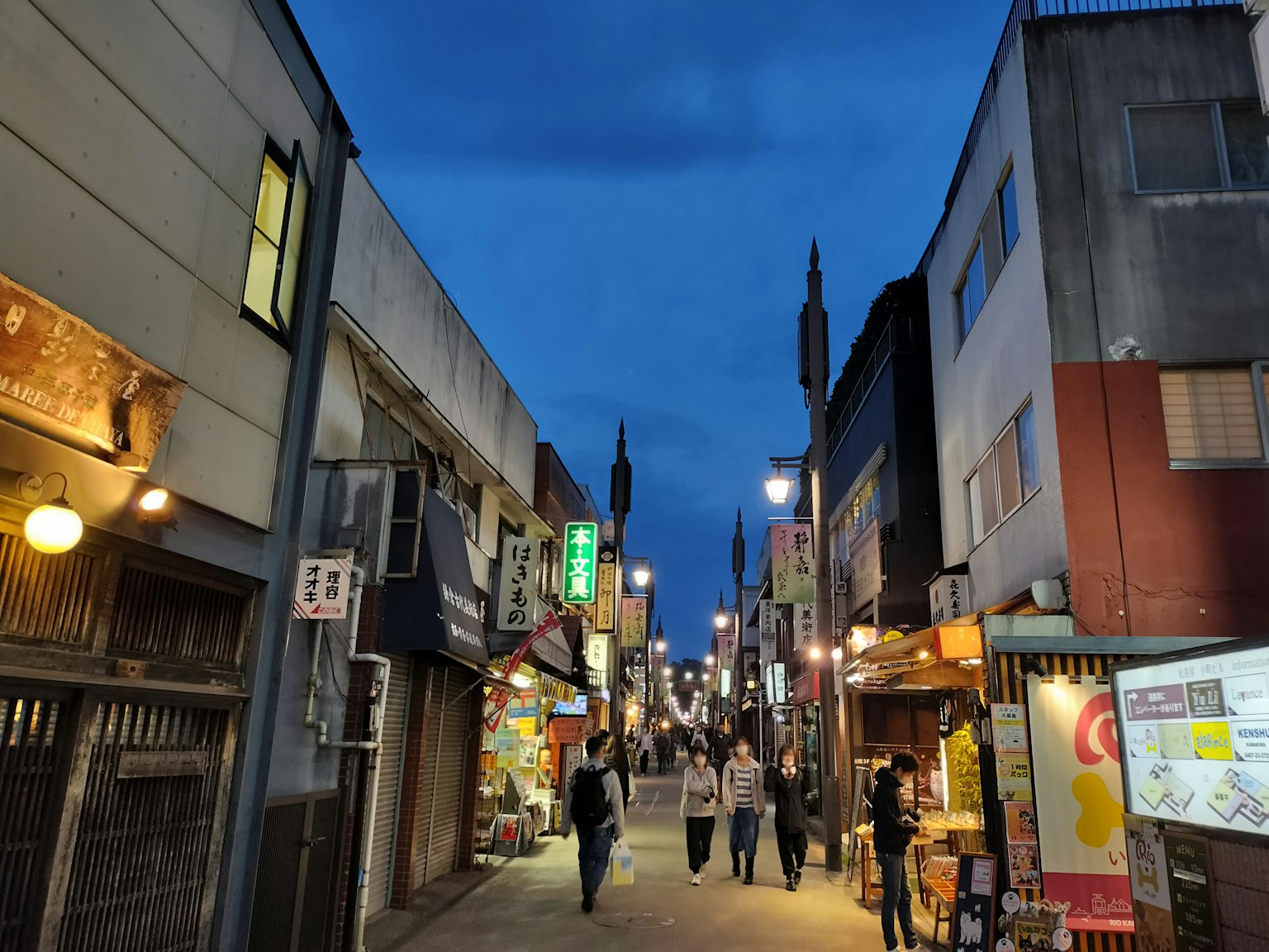 ทิวทัศน์ถนนในเวลากลางคืนมีผู้คนเดินและร้านค้ามากมาย
