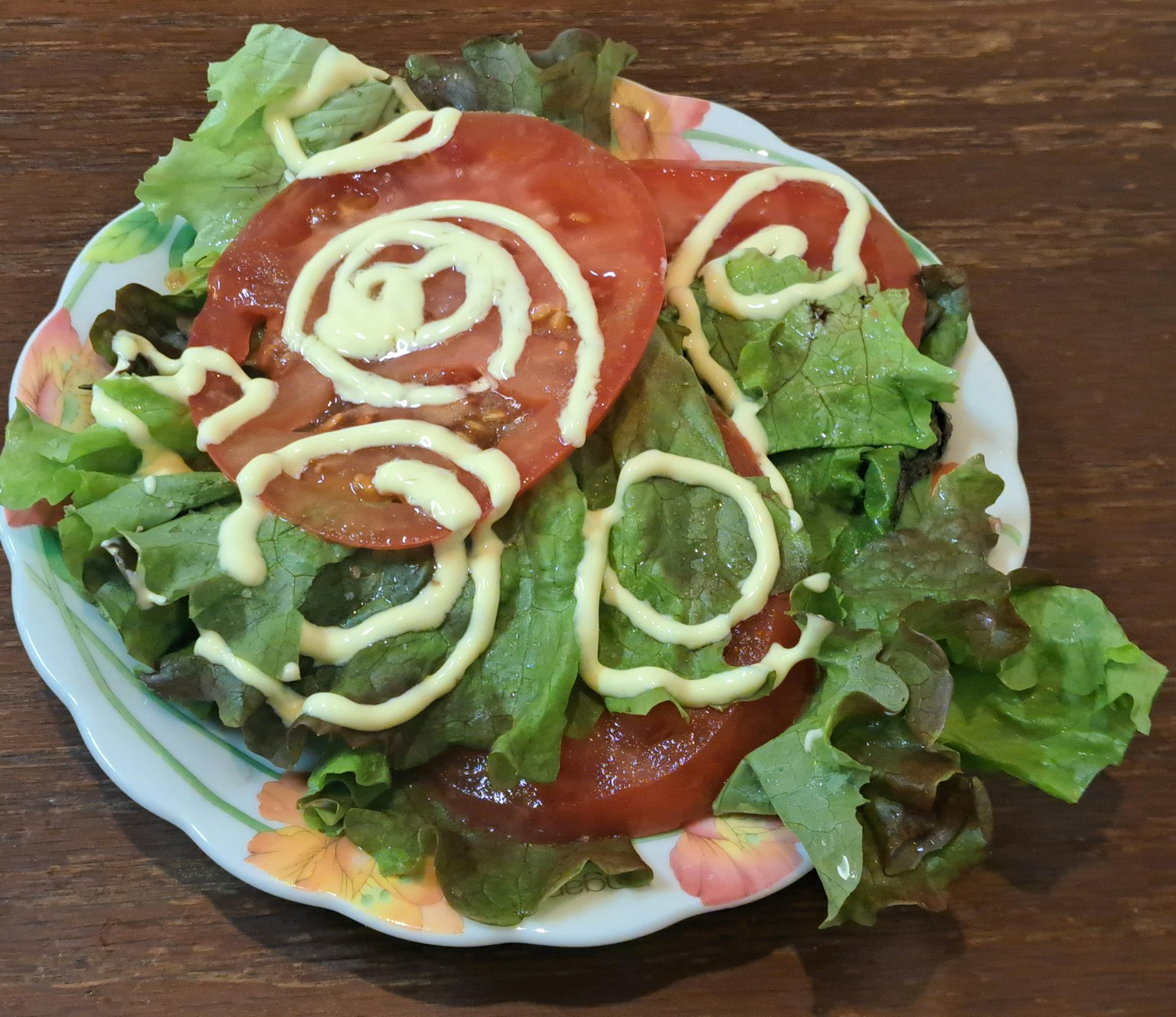 Ensalada de lechuga y tomate fresco con remolinos de mayonesa en un plato