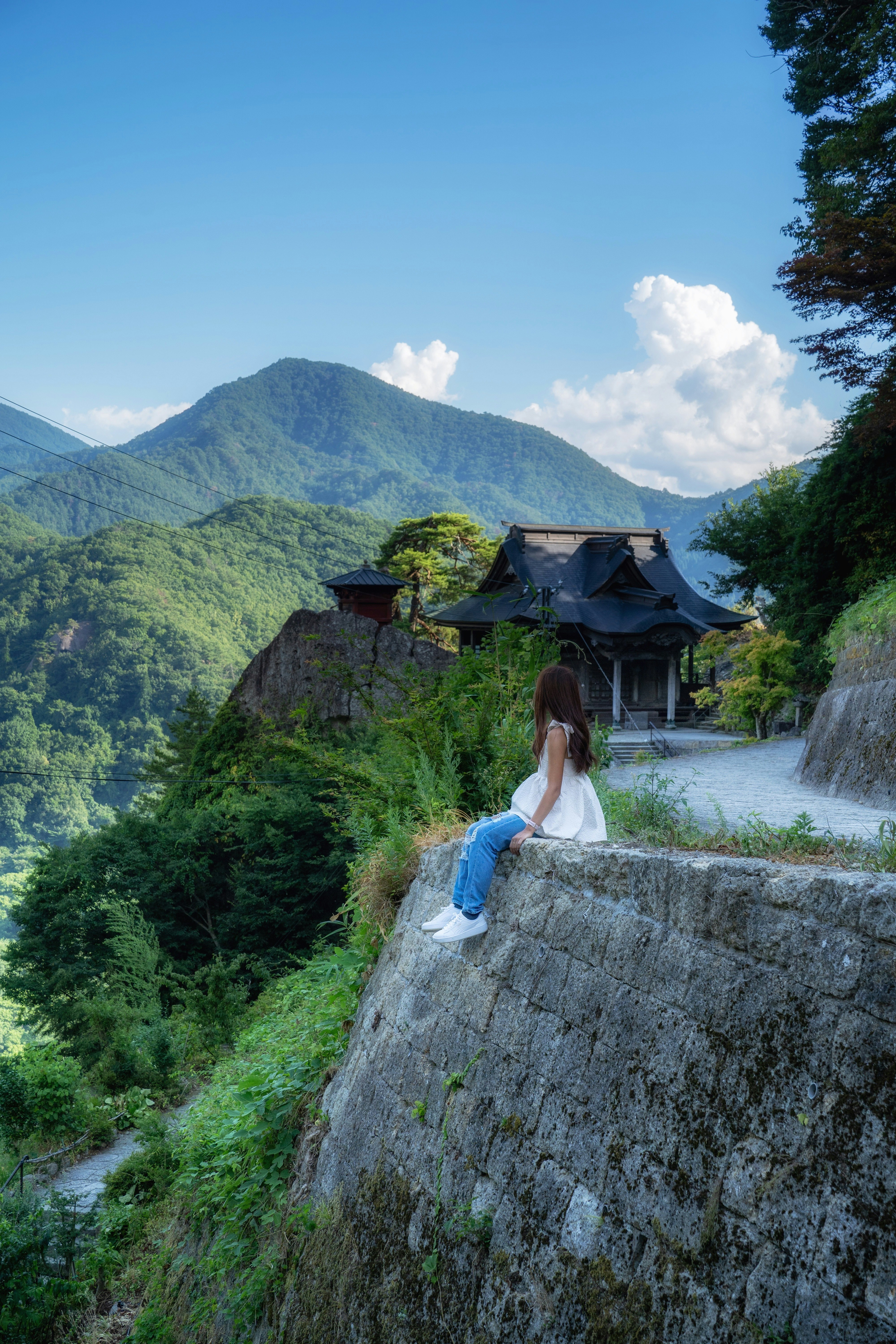 山寺の石段と緑の山並みを見下ろす夏のポートレート
