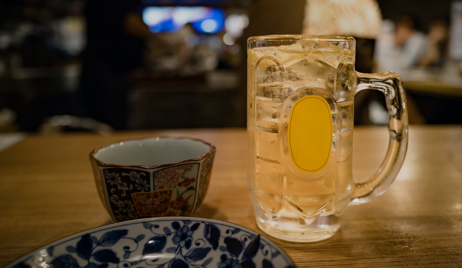 A clear beer mug and a small bowl are placed on a wooden table