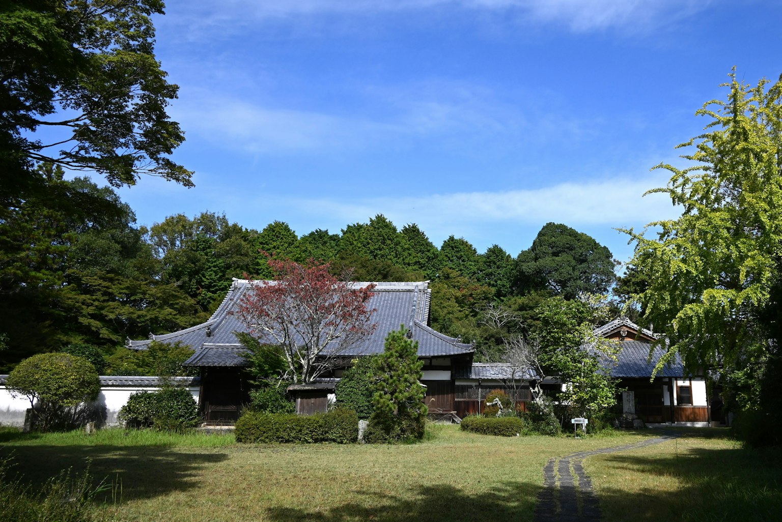 Bâtiment japonais traditionnel entouré d'un jardin paisible et d'un ciel bleu