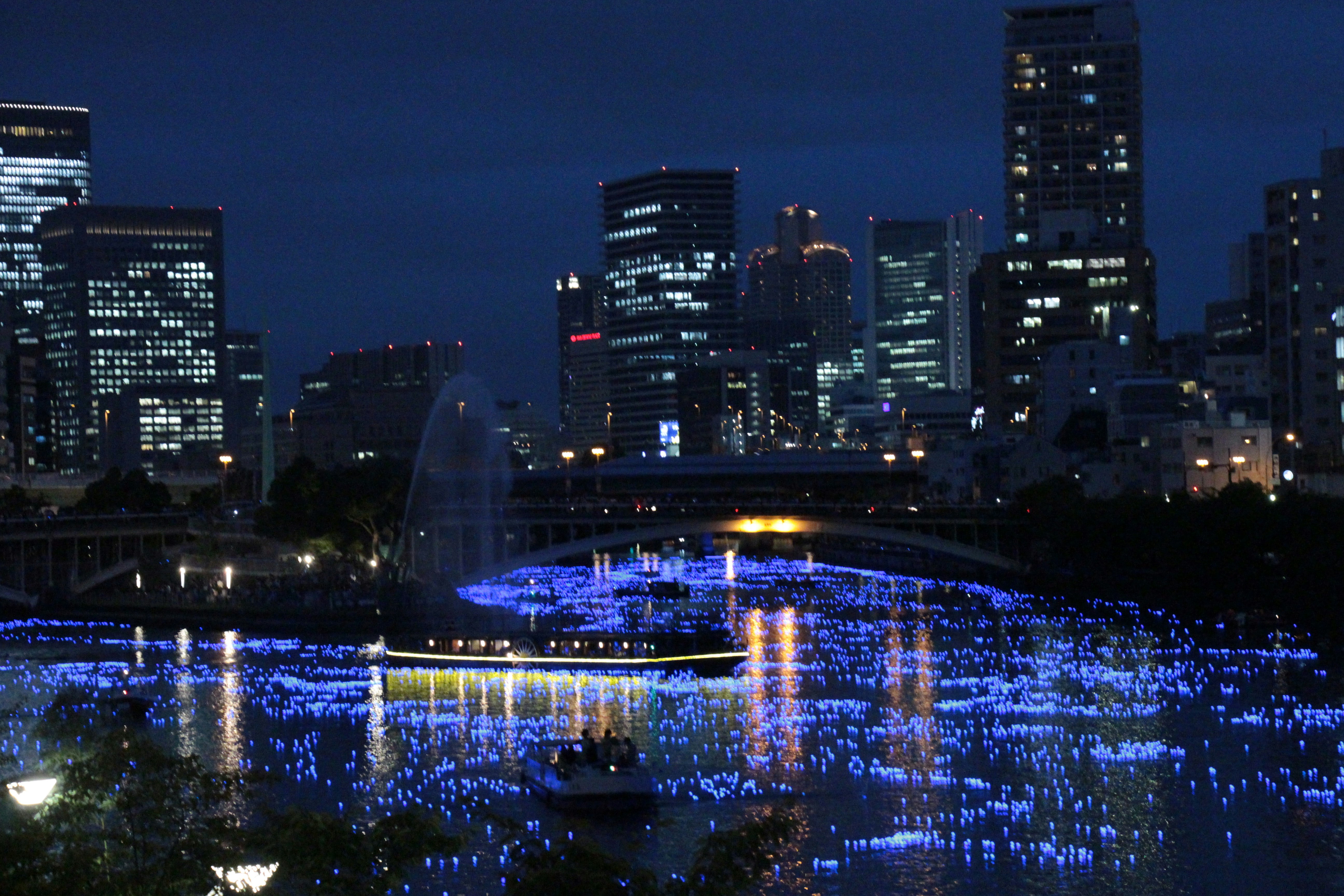ネオンのように光る夜景の都市と川沿いのイルミネーション画像