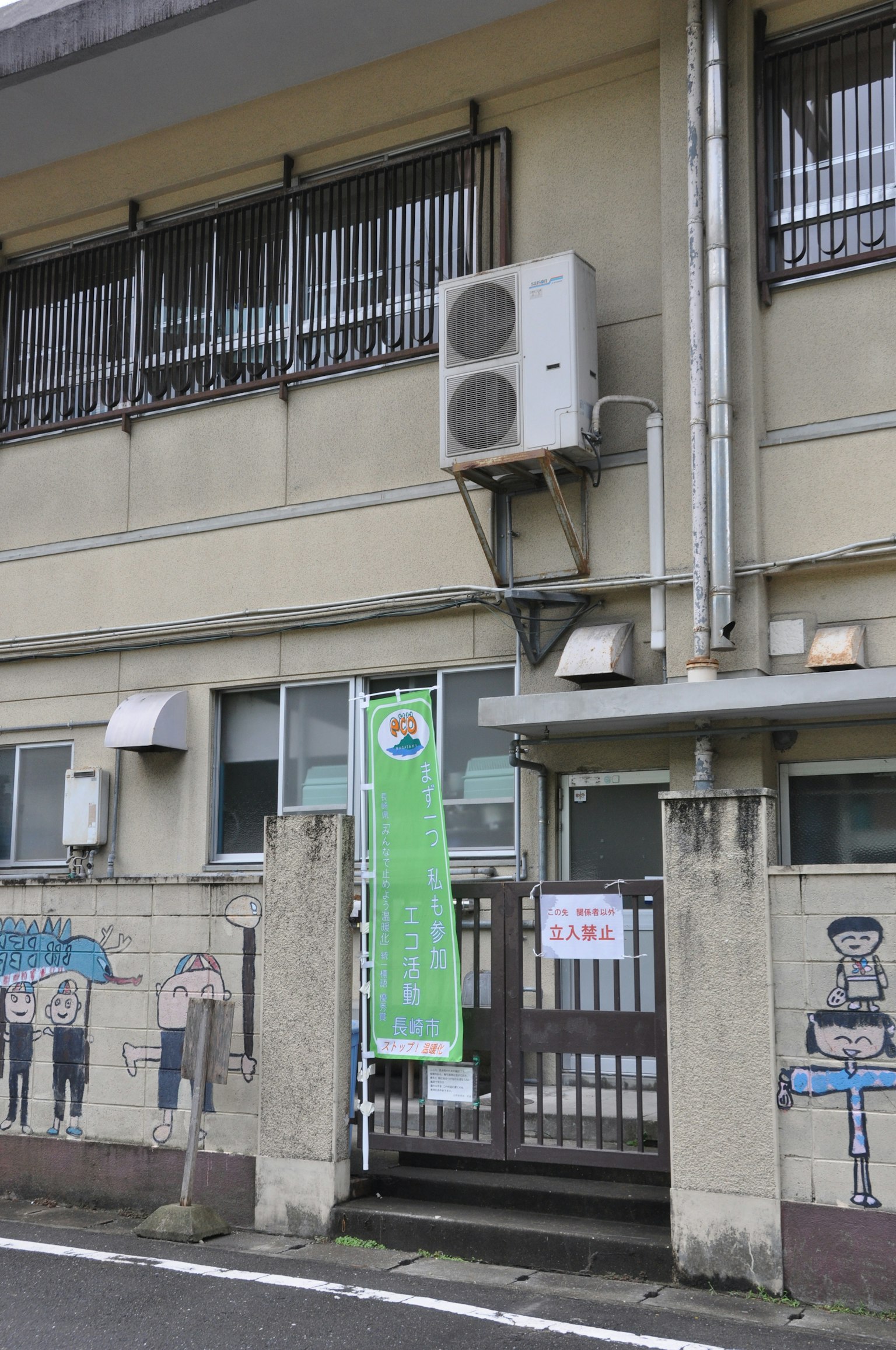 어린이 그림이 그려진 학교 입구 에어컨과 초록색 배너가 눈에 띄는