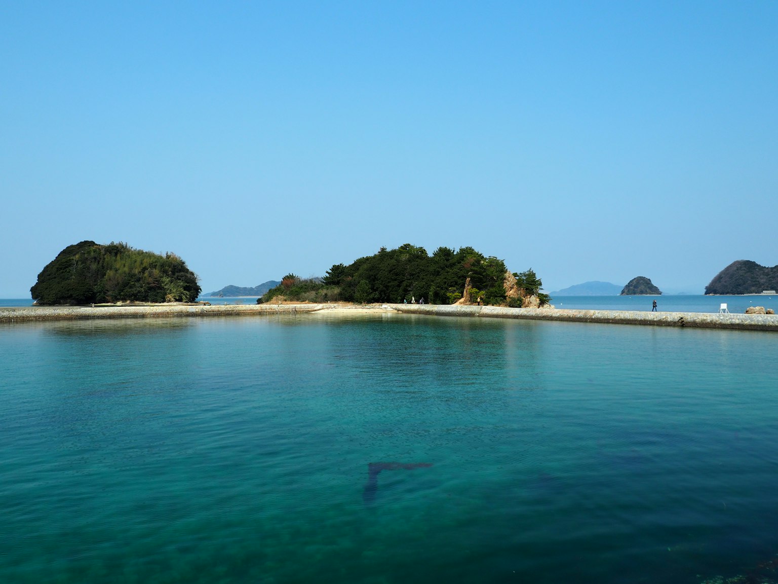 Scenic view of small islands surrounded by clear water and blue sky
