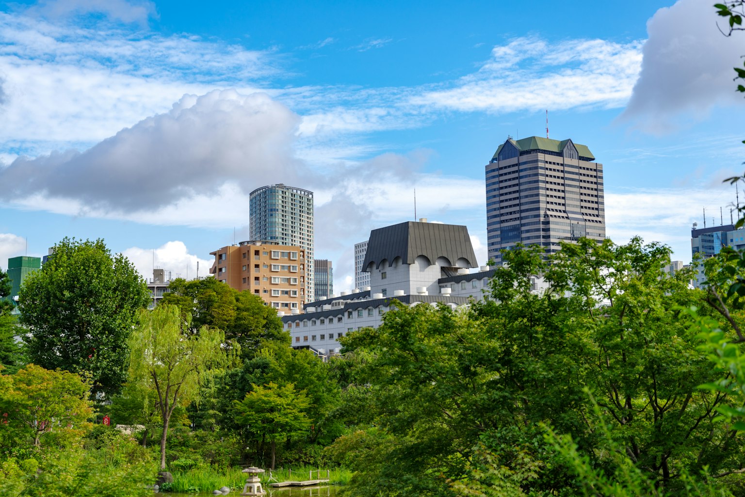 城市风景，绿树成荫的公园与蓝天和白云下的建筑
