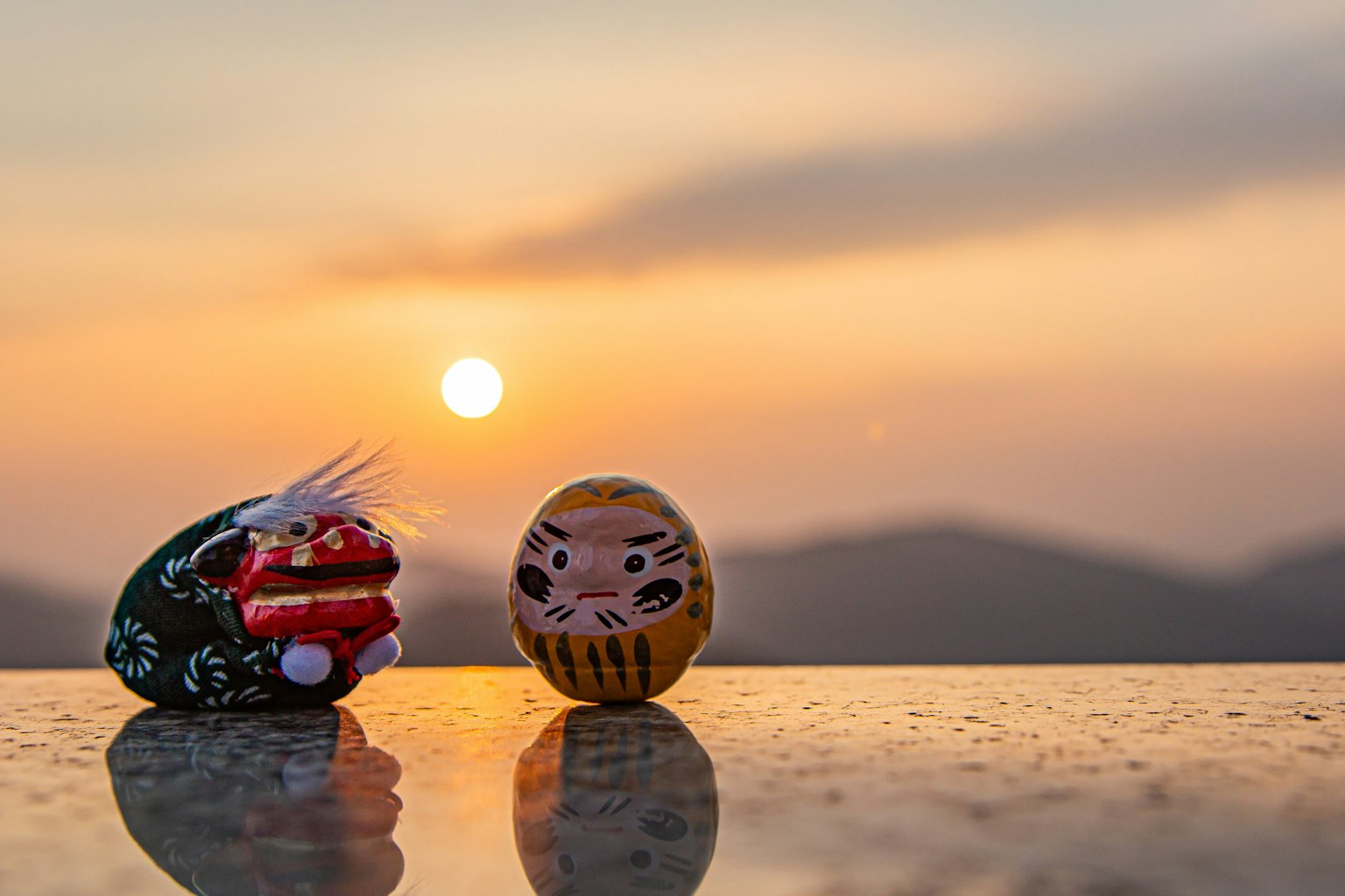 Zwei traditionelle Dekorationsfiguren vor einem Sonnenuntergang