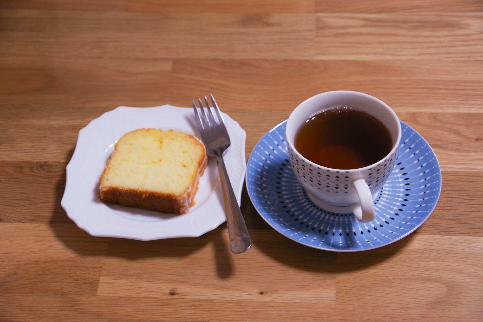 Una taza de té y una rodaja de pastel sobre una mesa de madera
