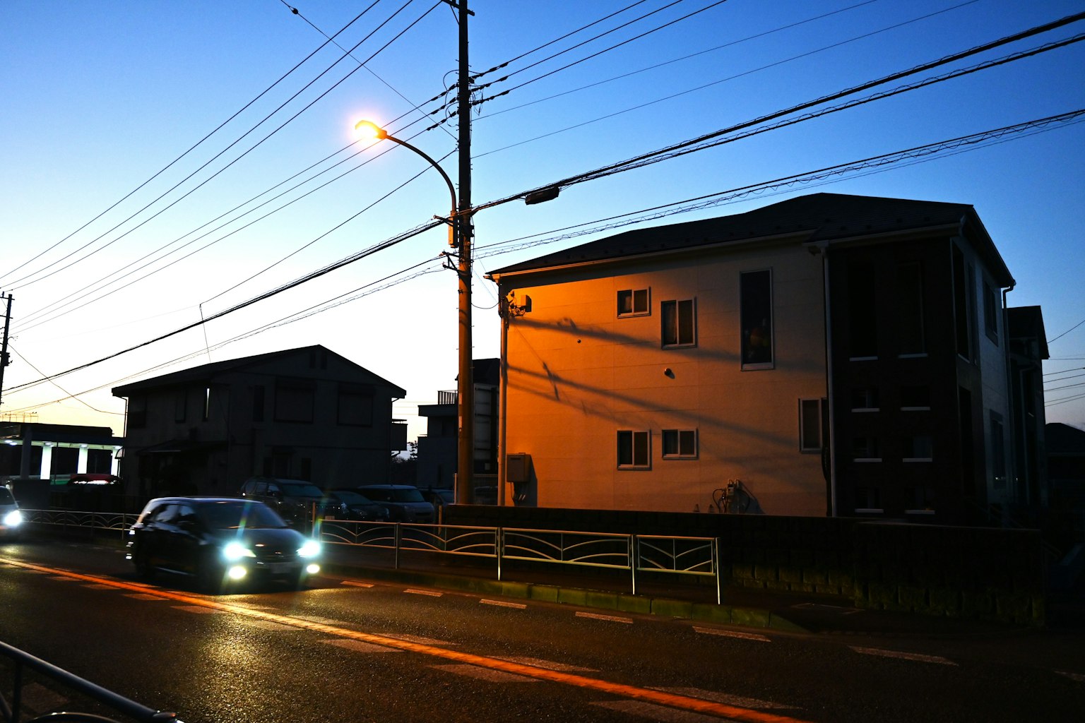 Scène nocturne avec une voiture passant et silhouette de bâtiments
