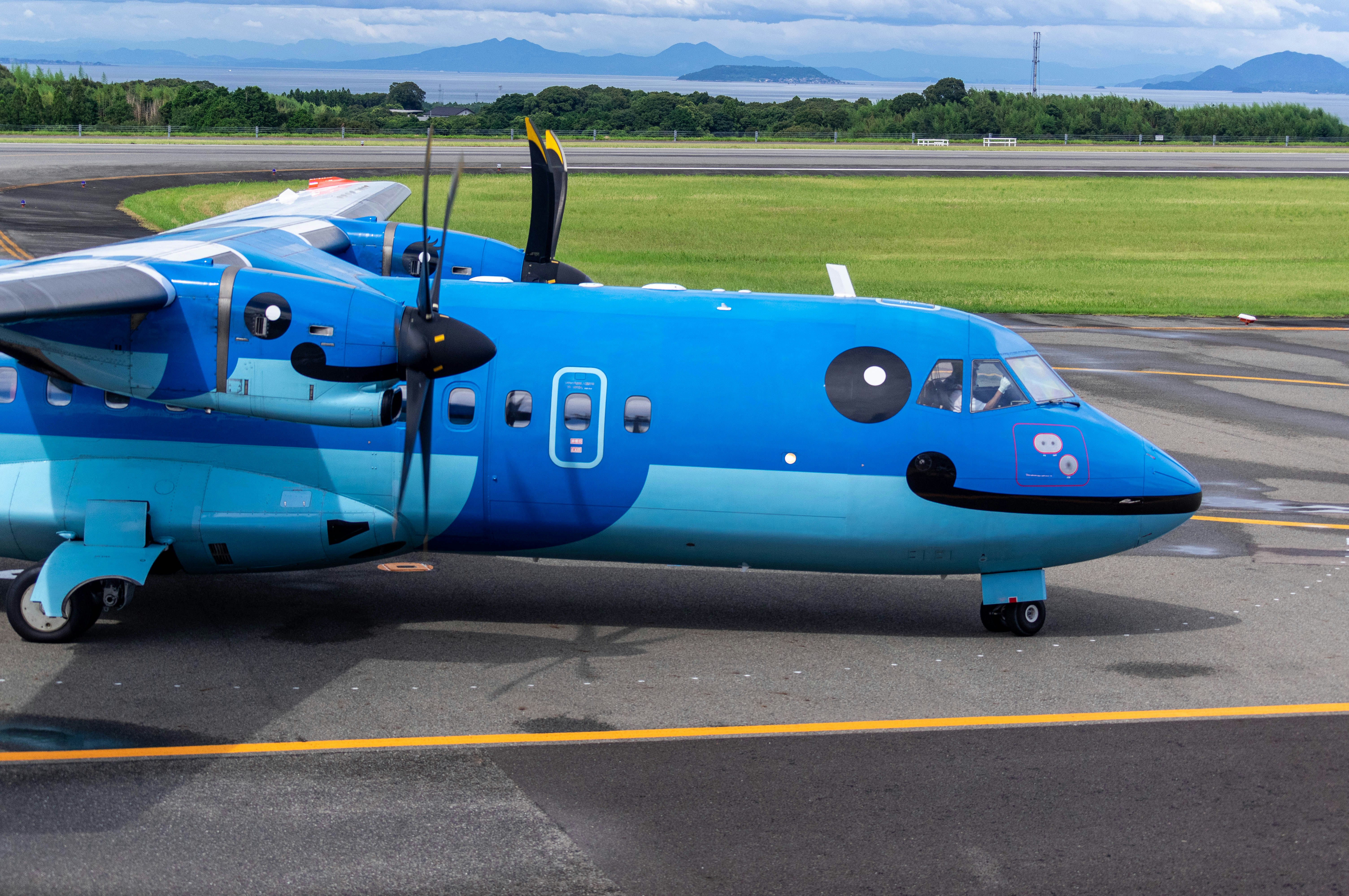 青い小型プロペラ機が滑走路で駐機している