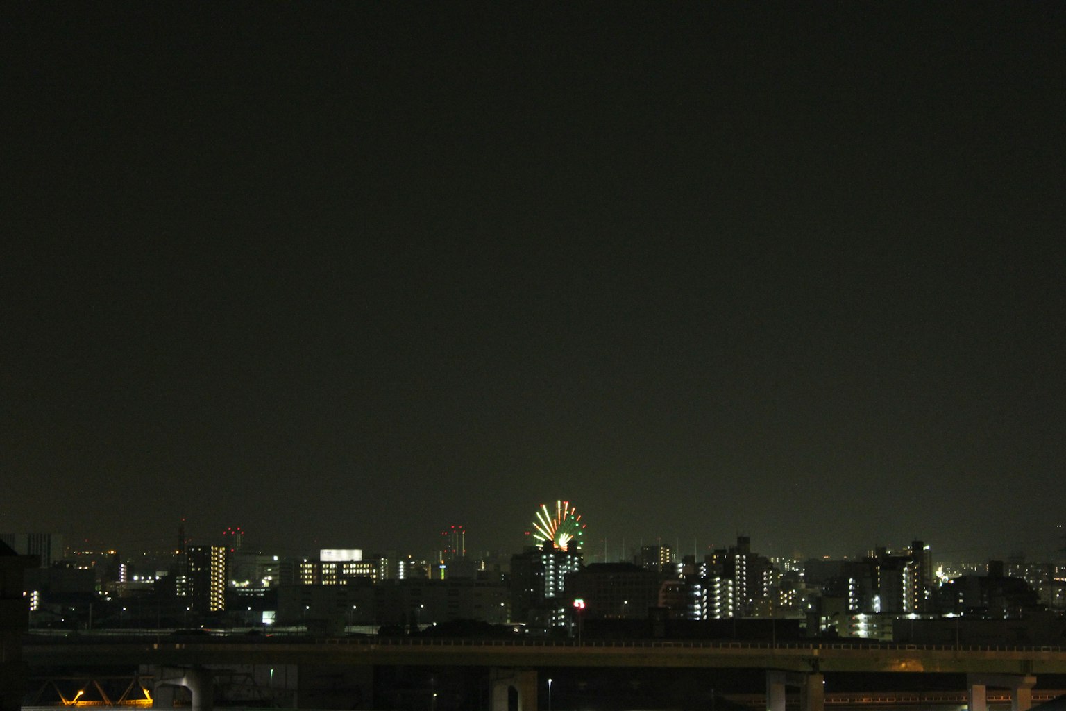 Vista notturna dello skyline di una città con una ruota panoramica illuminata