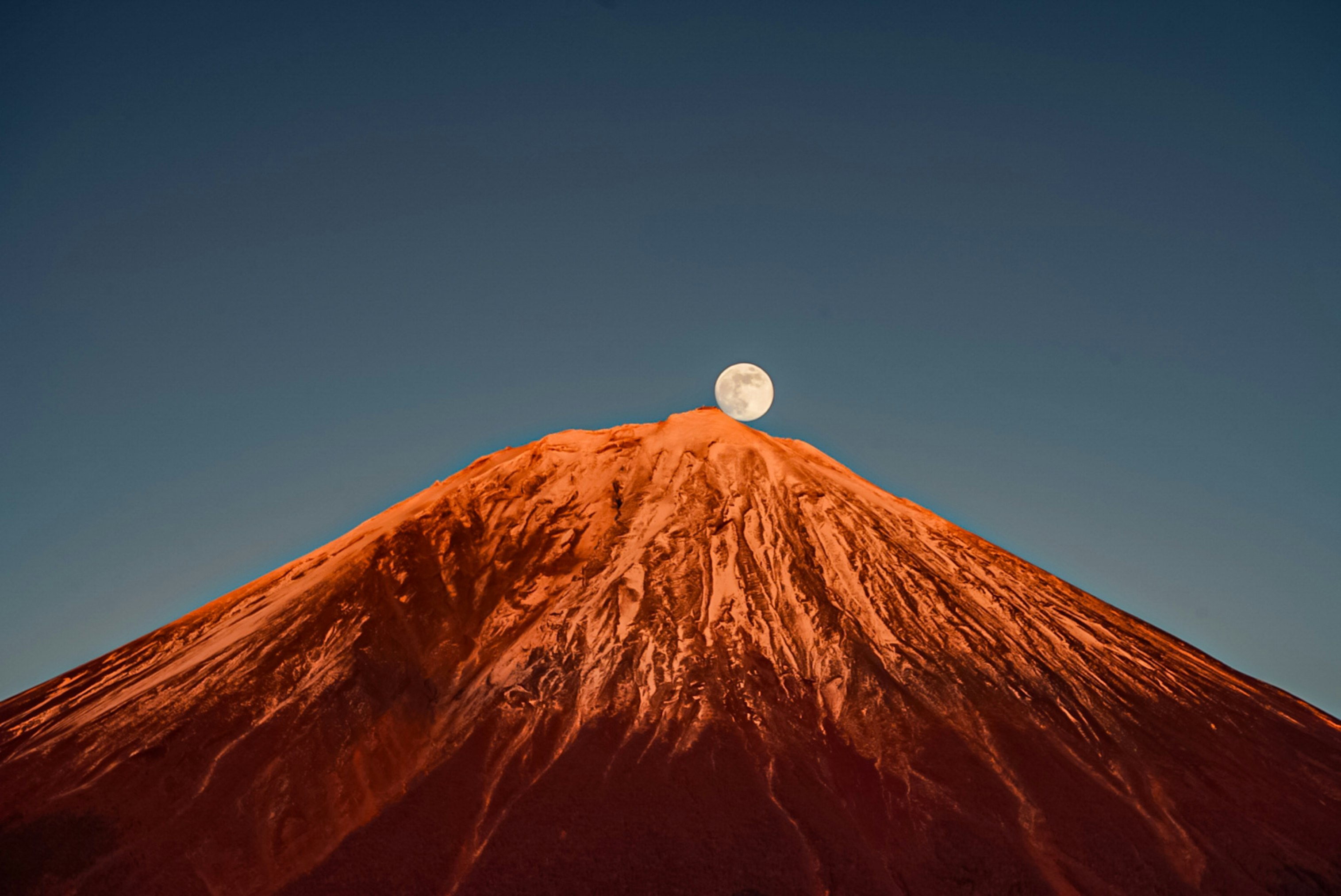 夕焼けの空に浮かぶ赤い火山の山頂