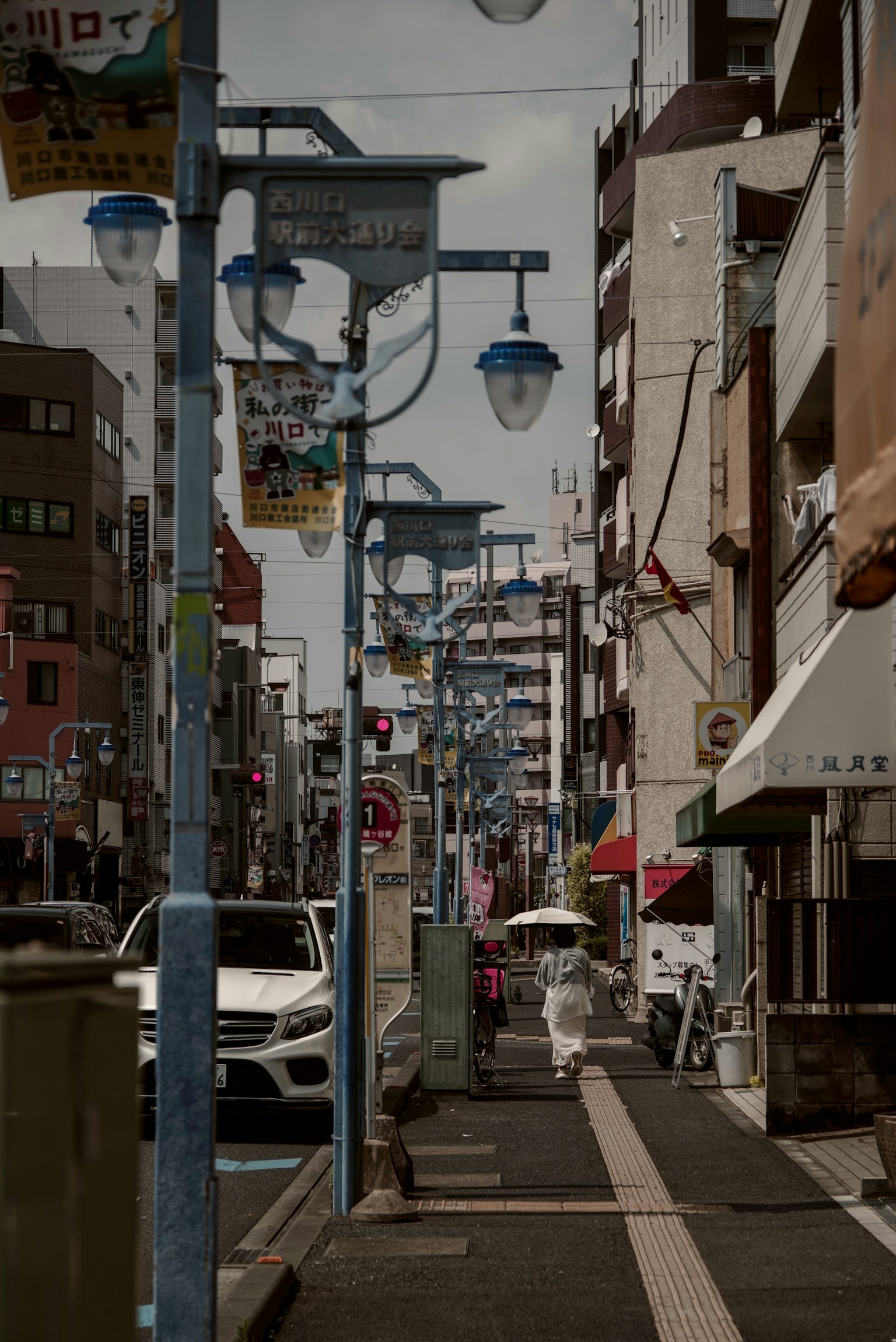 Street view in Japan featuring blue street lamps cars and pedestrians