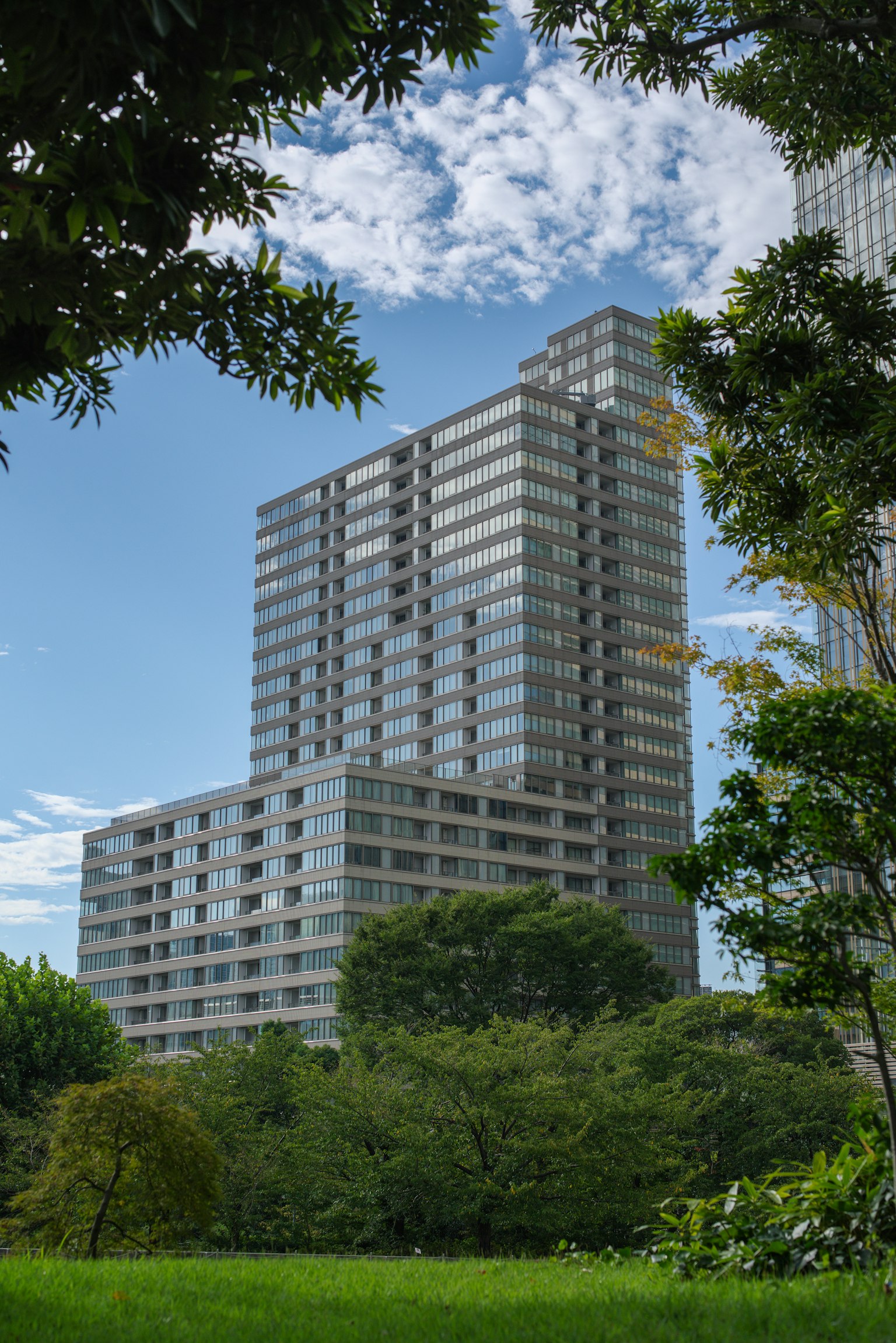 Gratte-ciel moderne entouré de verdure sous un ciel bleu