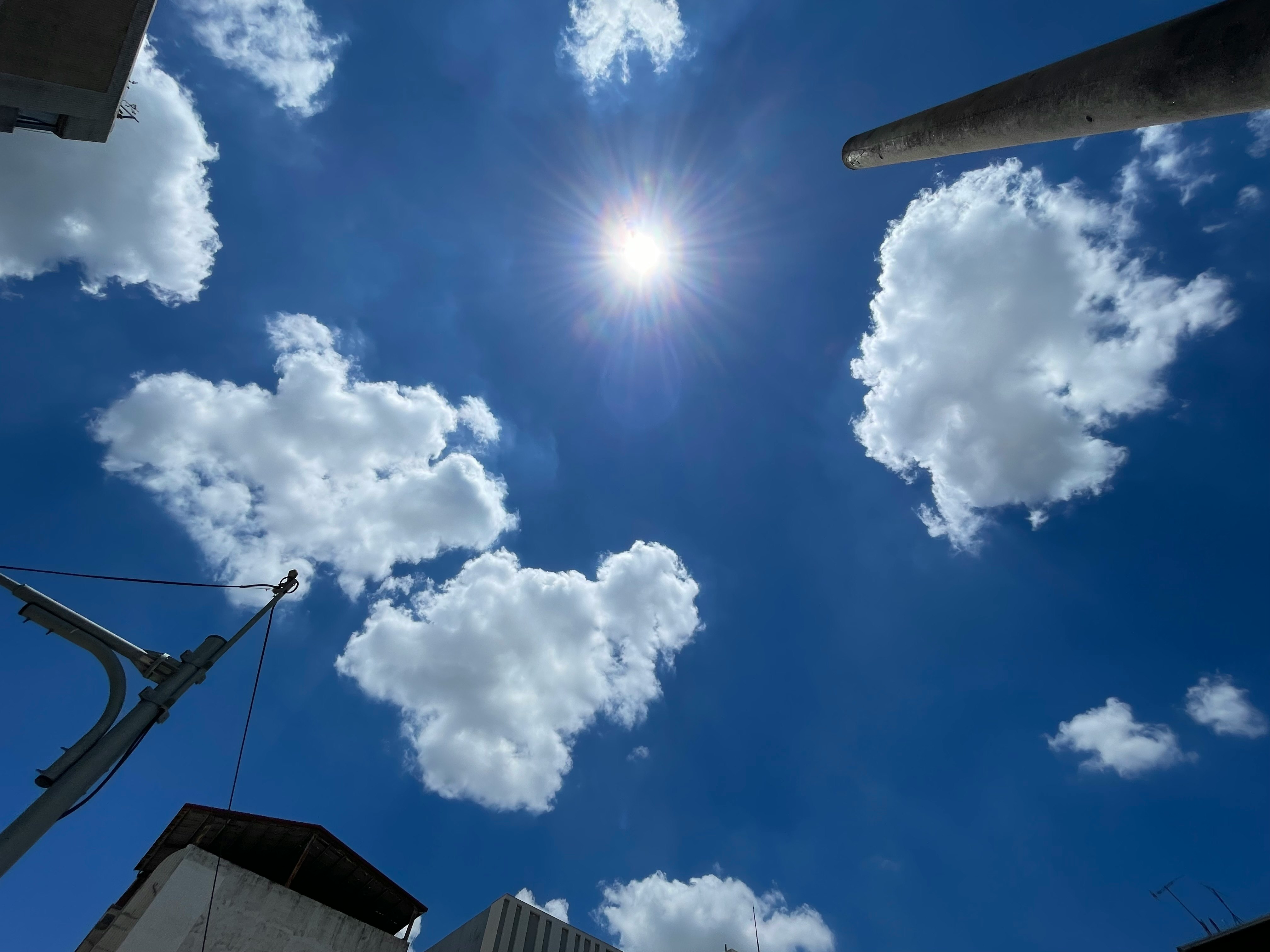 青空に浮かぶ雲と太陽の光が差す空の見上げ景色