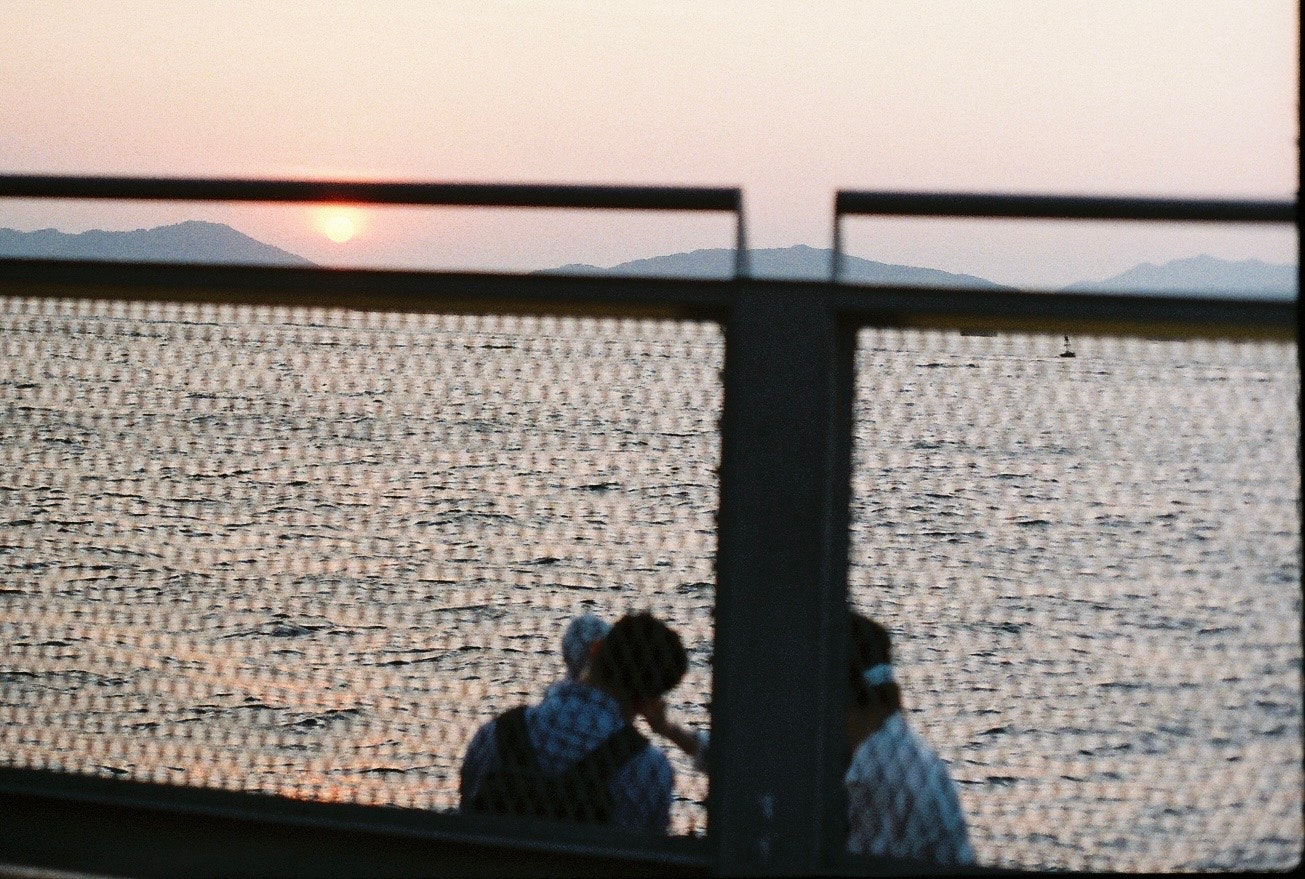 夕暮れの海を眺める人々のシルエット