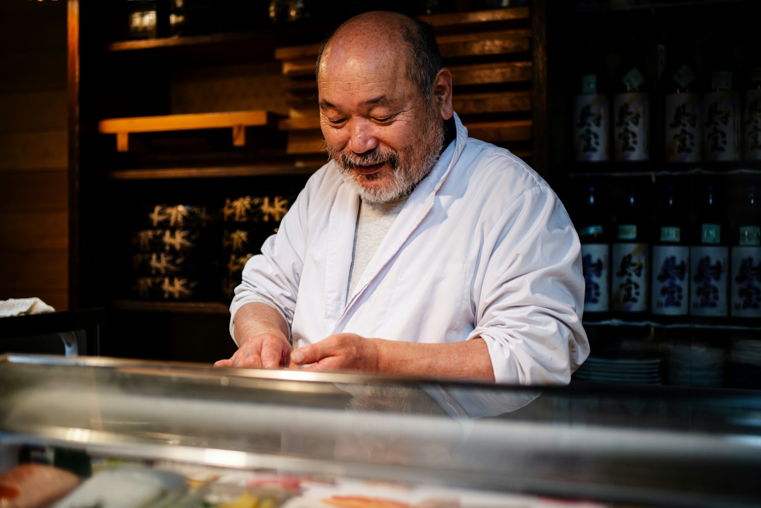 Koki tersenyum yang sedang menyiapkan sushi dengan ekspresi fokus