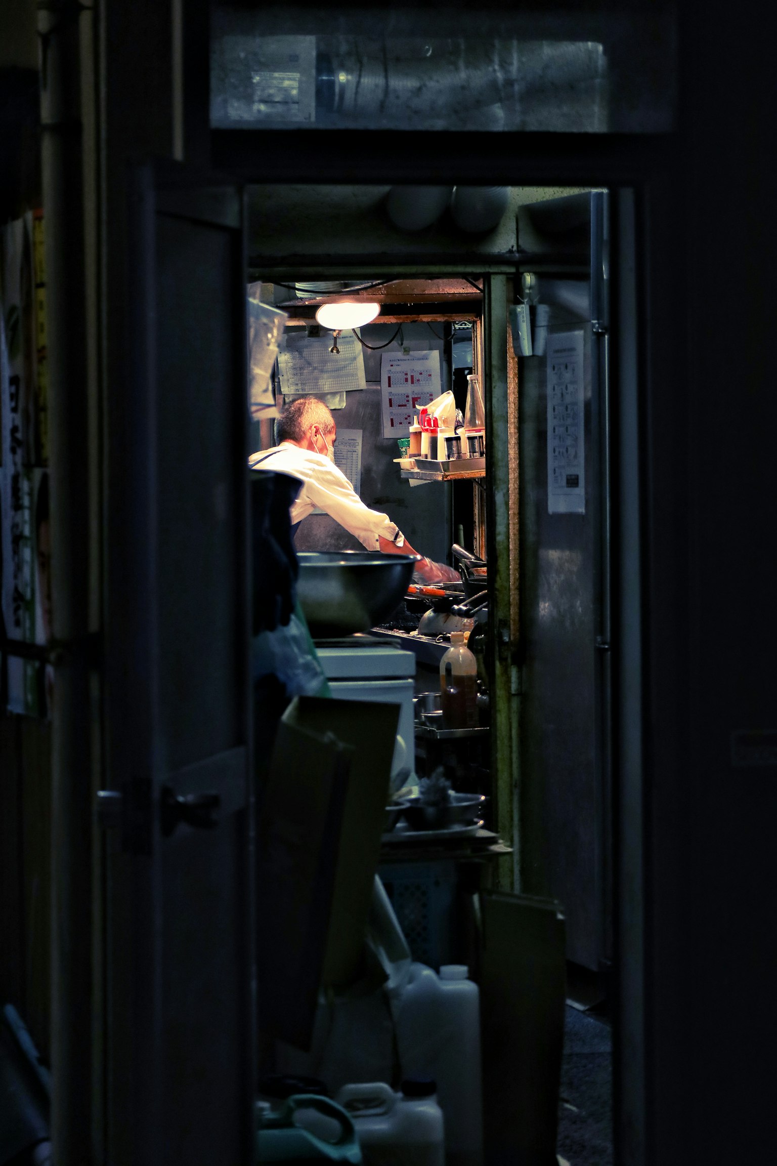 暗い通路の奥にいる料理人が調理している様子