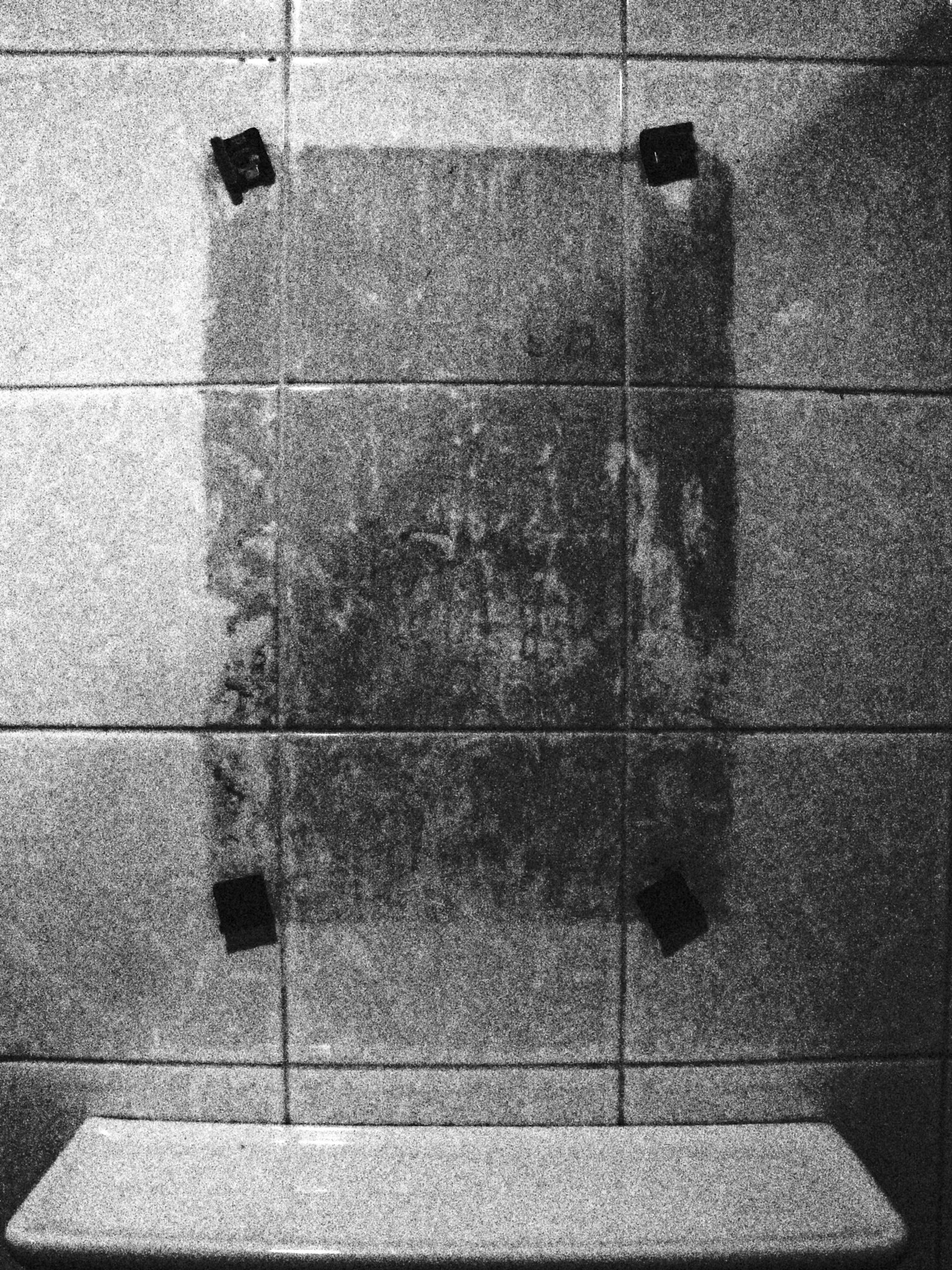 Panel de vidrio empañado montado en una pared de azulejos con cinta negra