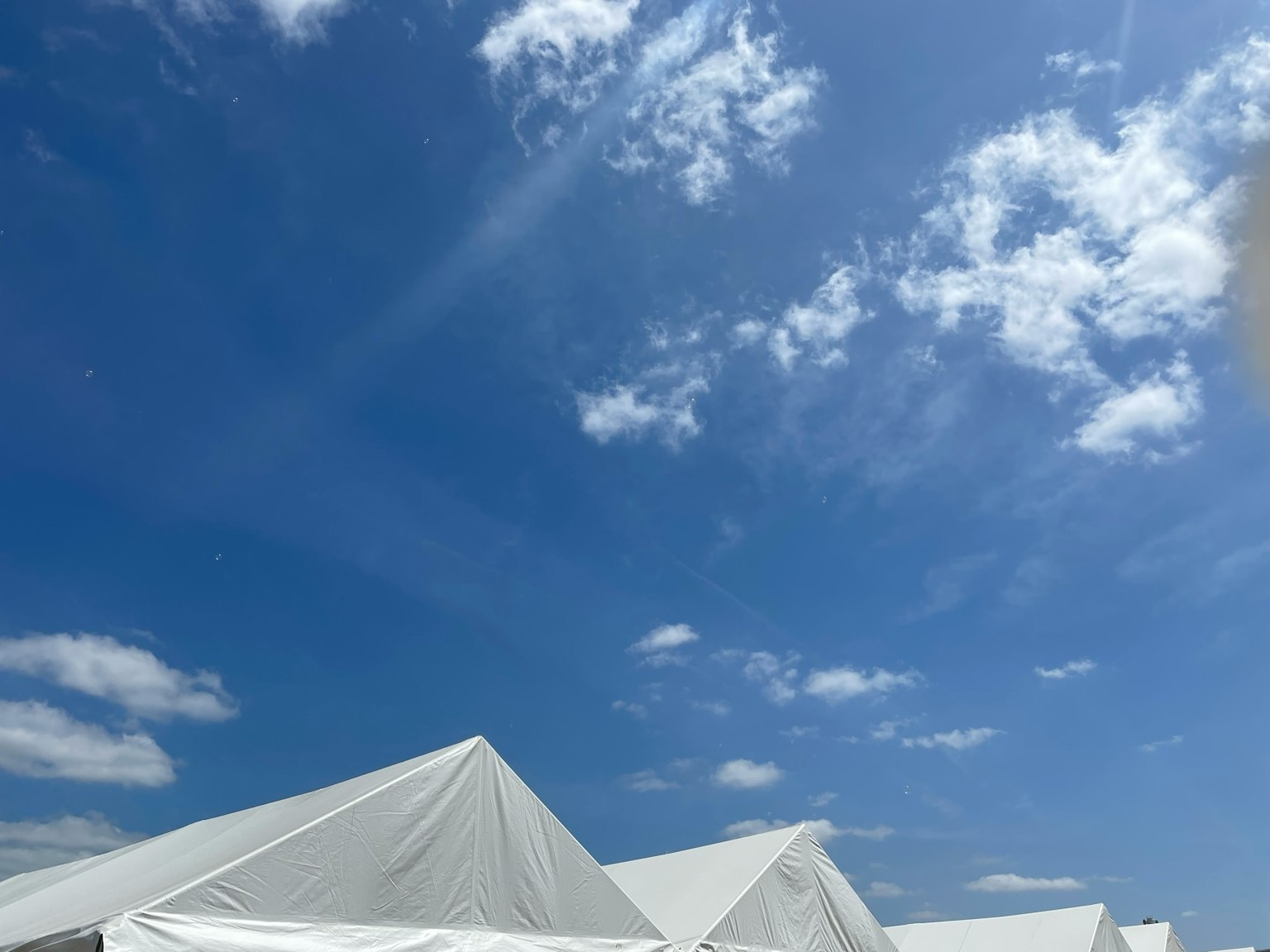 Une scène avec des tentes blanches sous un ciel bleu