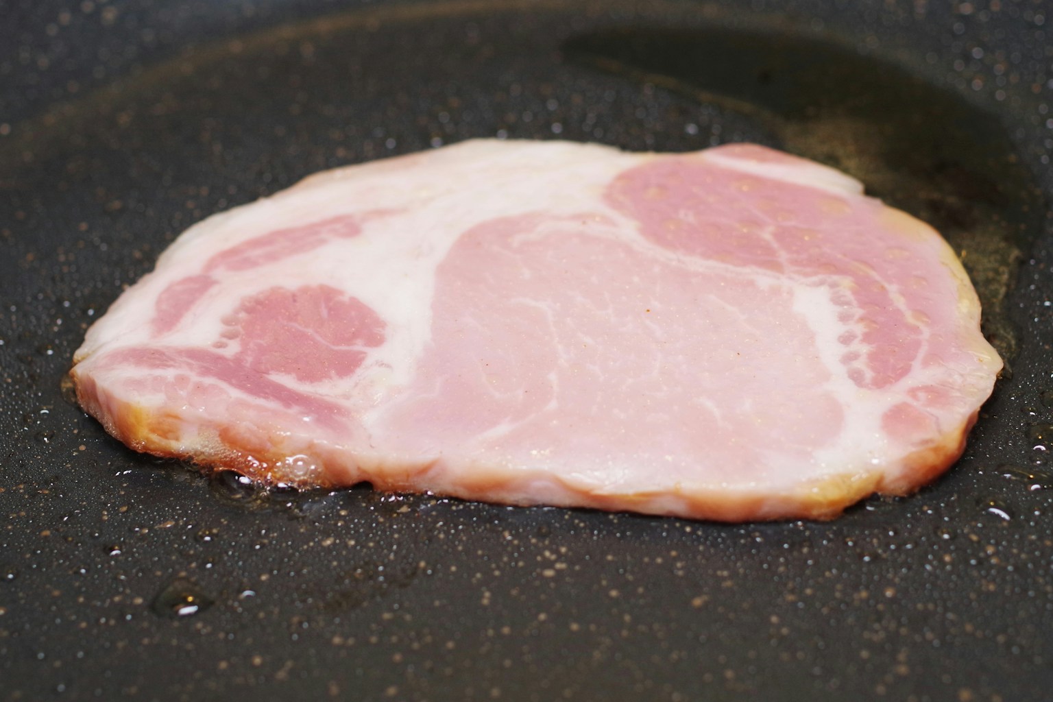 Slice of pork cooking in a frying pan