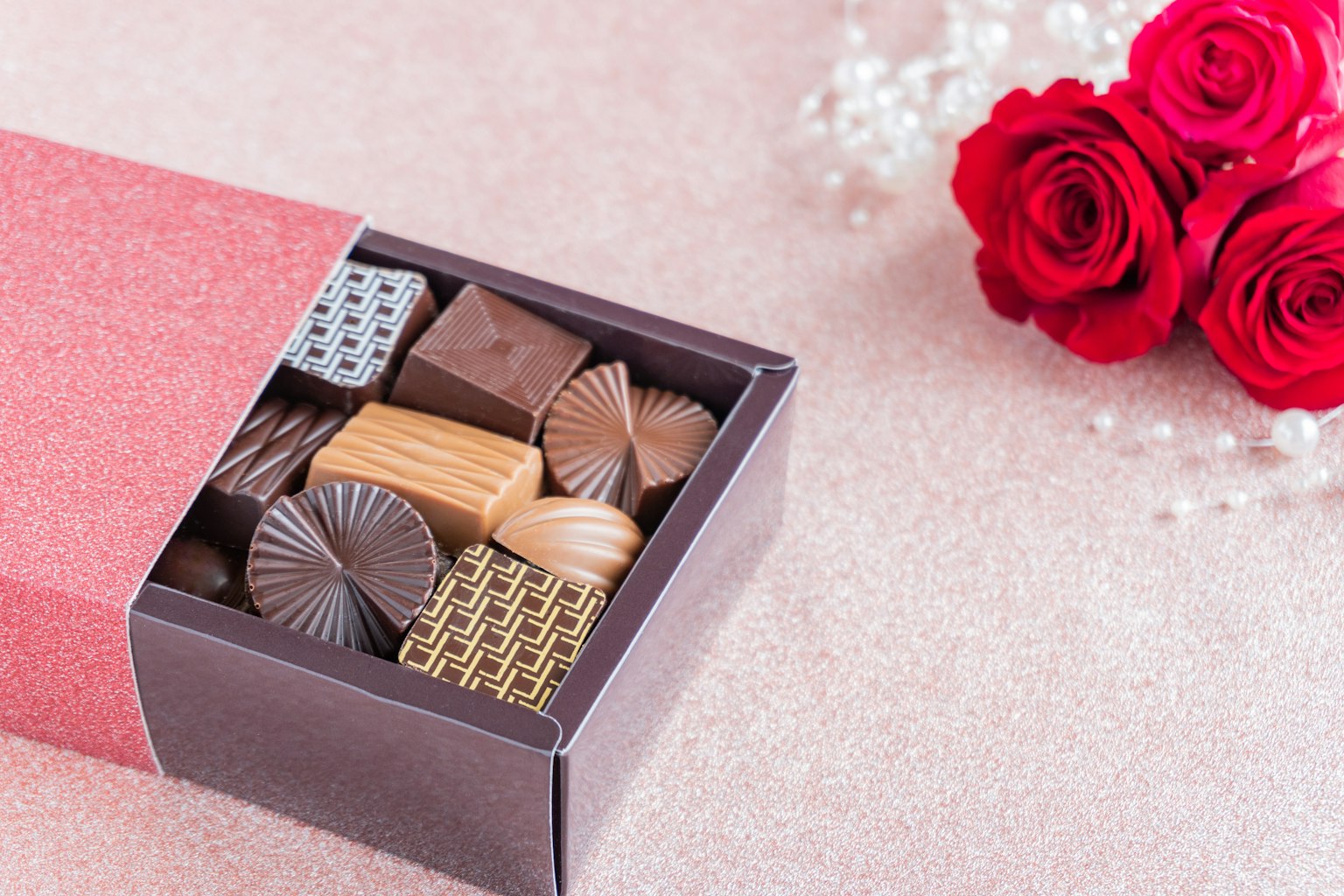 Image of a box filled with chocolates alongside red roses