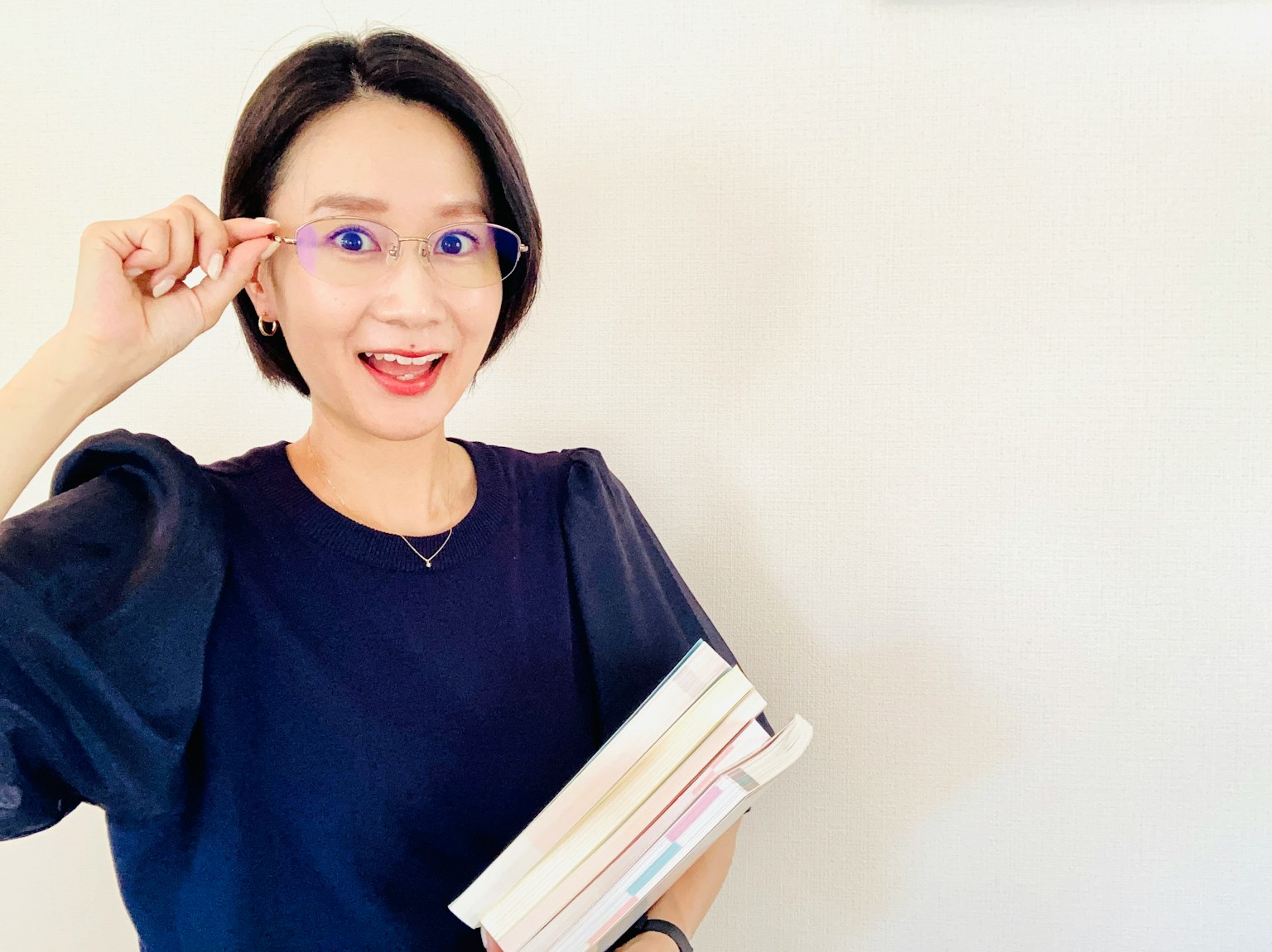 Một người phụ nữ mỉm cười cầm sách với kính