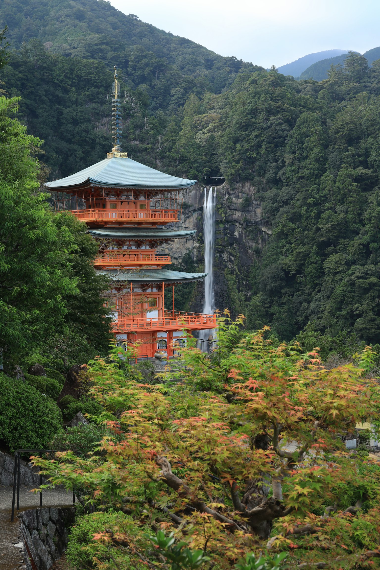 Vista panoramica di una pagoda circondata da foglie autunnali e una cascata