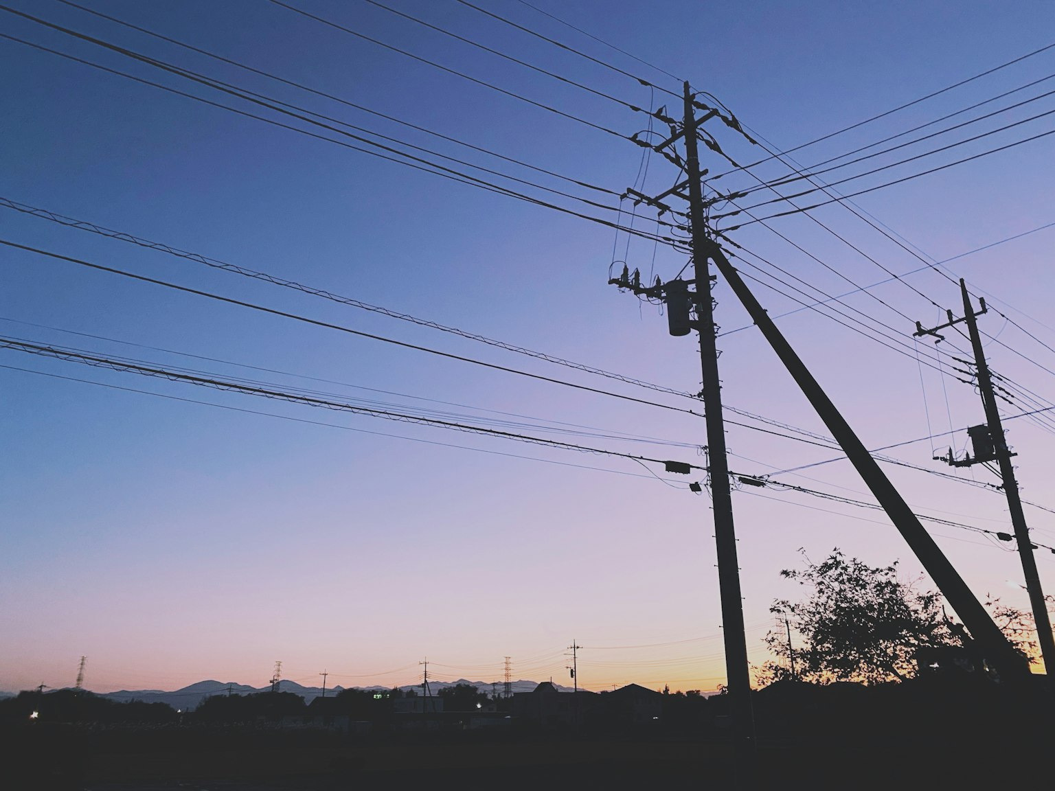 Silhouette de poteaux électriques et de fils au crépuscule