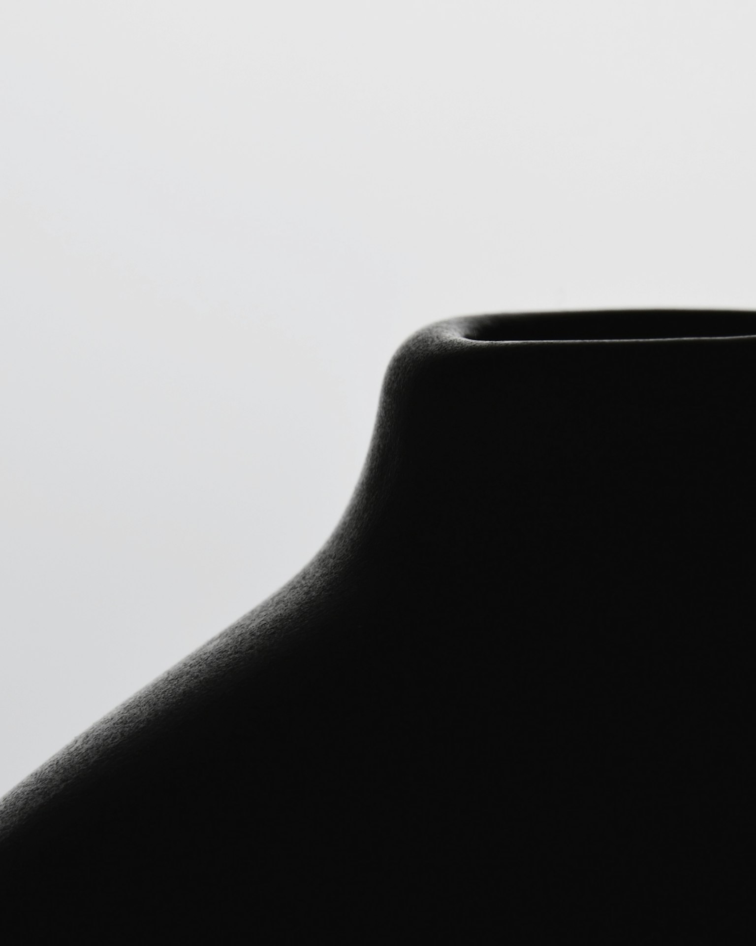 Close-up of the top of a black vase with smooth contours