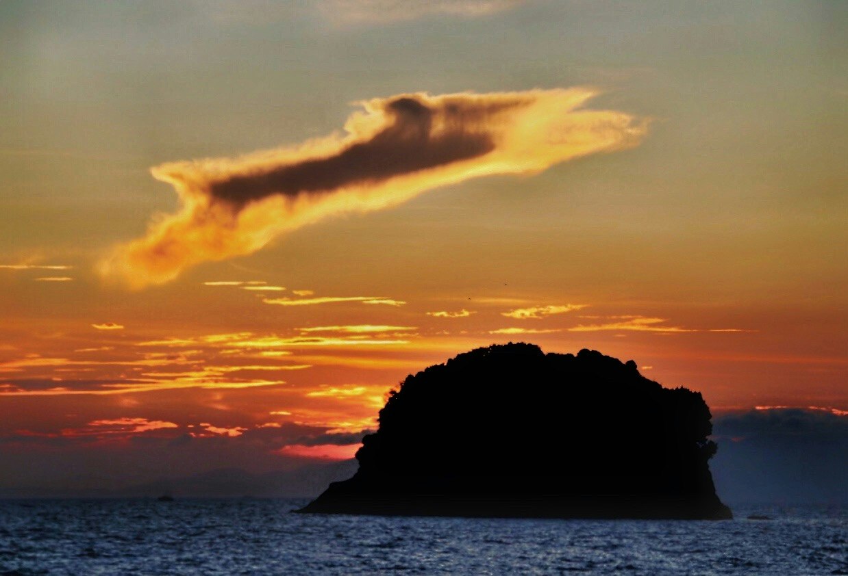 夕陽下海面上小島的剪影與像狐狸般的雲