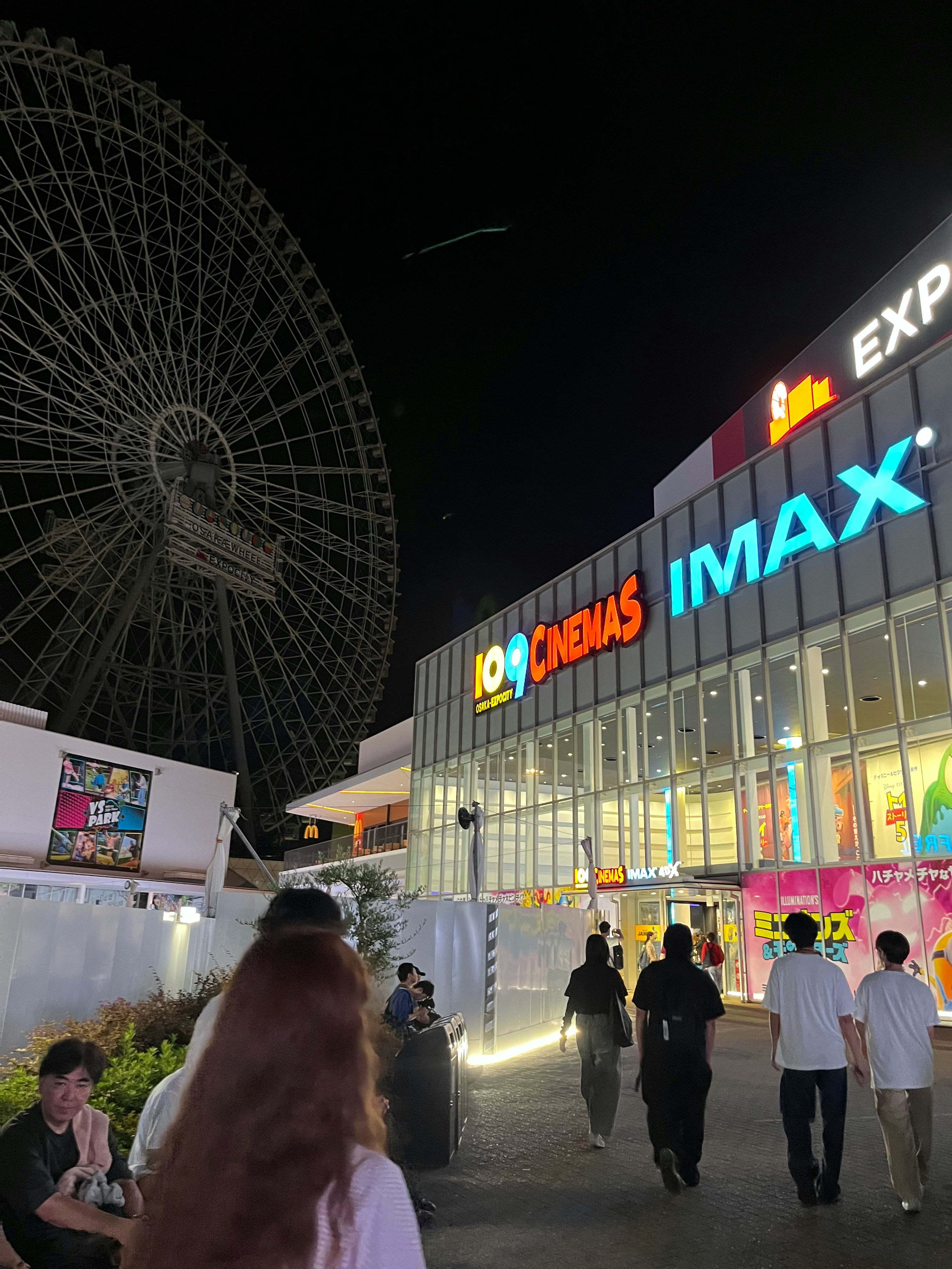 夜の大型商業施設前で人が行き交う光景