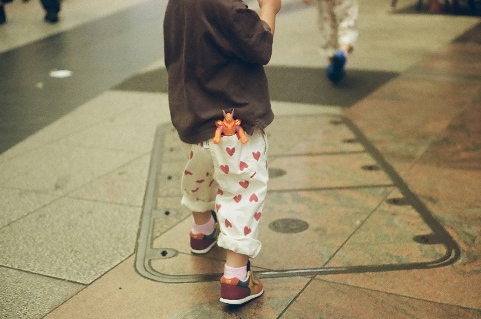 Enfant portant un pantalon à motifs de cœurs vu de dos